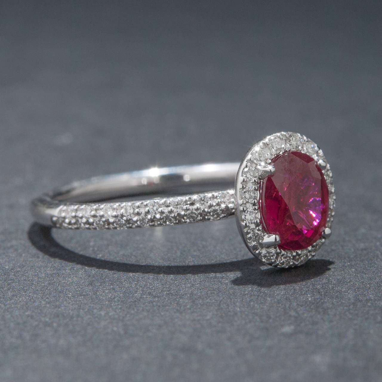 A vibrant and eye-catching ring with a .83 carat oval cut ruby at its center. The center stone is surrounded by 48 accent diamonds weighing a total of .22 carats. The ring is made in 18k white gold and it is currently size 6 1/4.