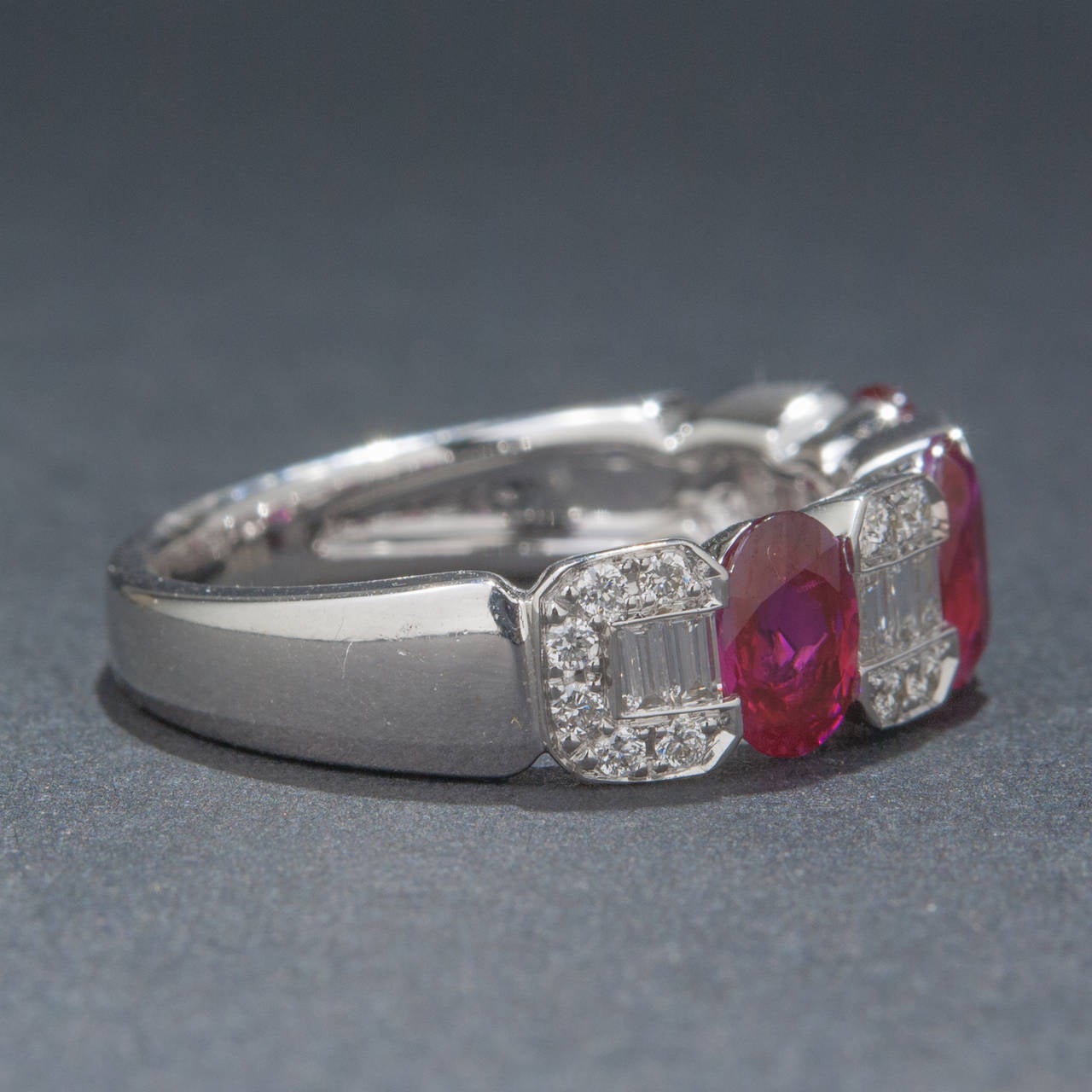 A gorgeous ruby and diamond half-eternity band made in eye-catching 18k white gold. This piece features 3 rubies for a total of 1.95 carats, 10 baguette cut diamonds for .17 total carats and 20 round brilliant diamonds for .18 total carats. The ring