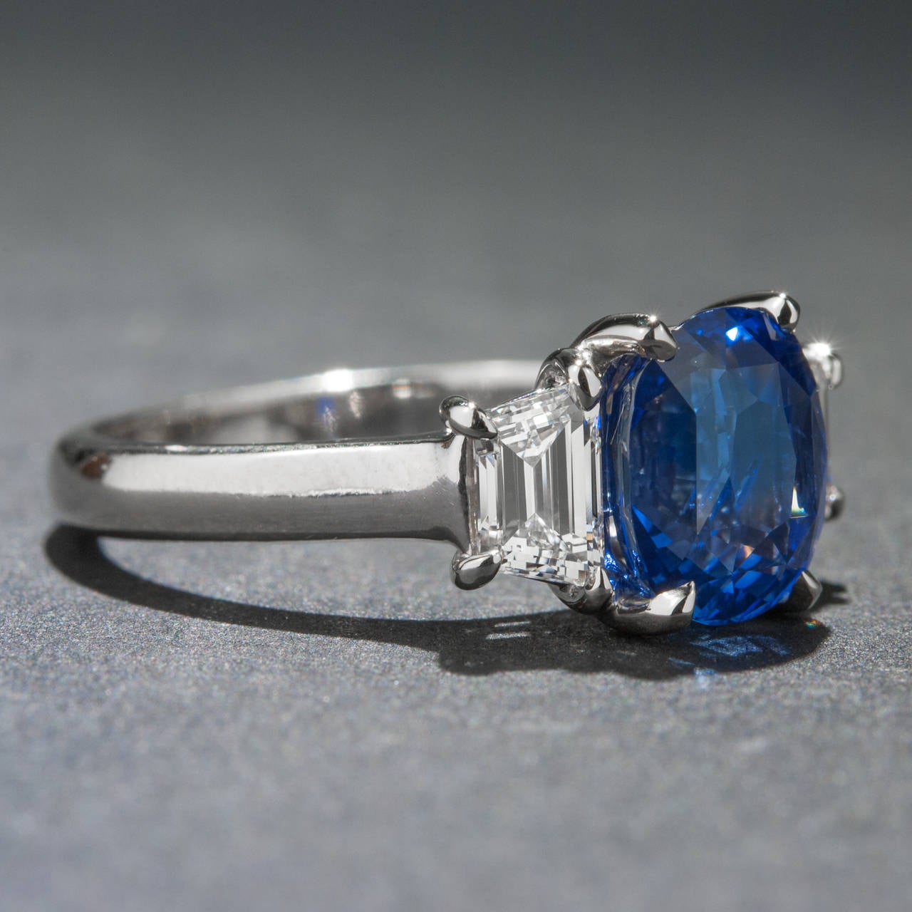 A beautiful sapphire, diamond and 14k white gold ring crafted circa 1960. This vibrant piece features a lovely 2.54 carat oval cut sapphire and two side diamonds for .70 total carats. The ring is currently size 6 and it can be sized to fit.