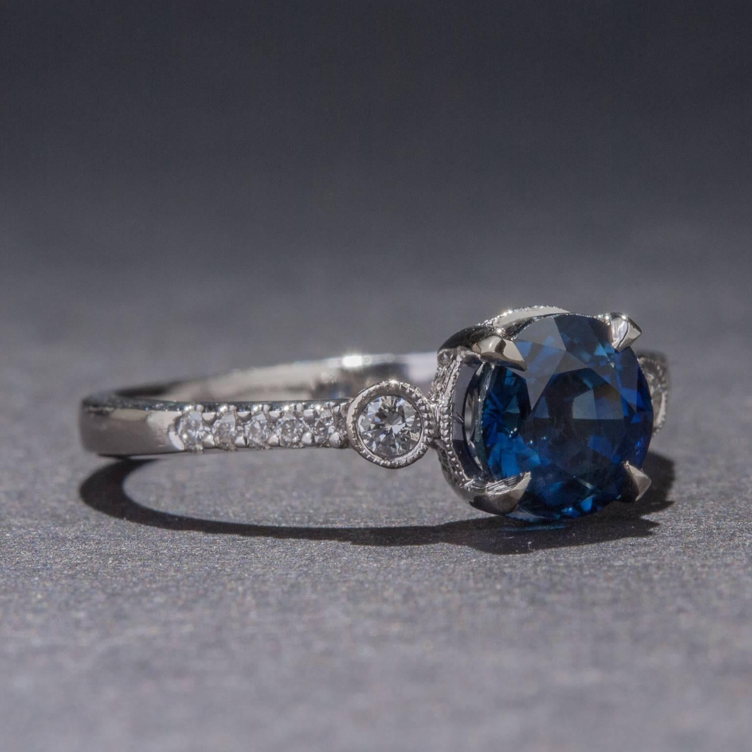 Deep blue sapphire color radiates from this elegant 18k white gold ring. The round sapphire weighs 2.01 carats and is complemented by .28 carats of diamonds. This is a classic ring design with vibrant color and diamond sparkle.