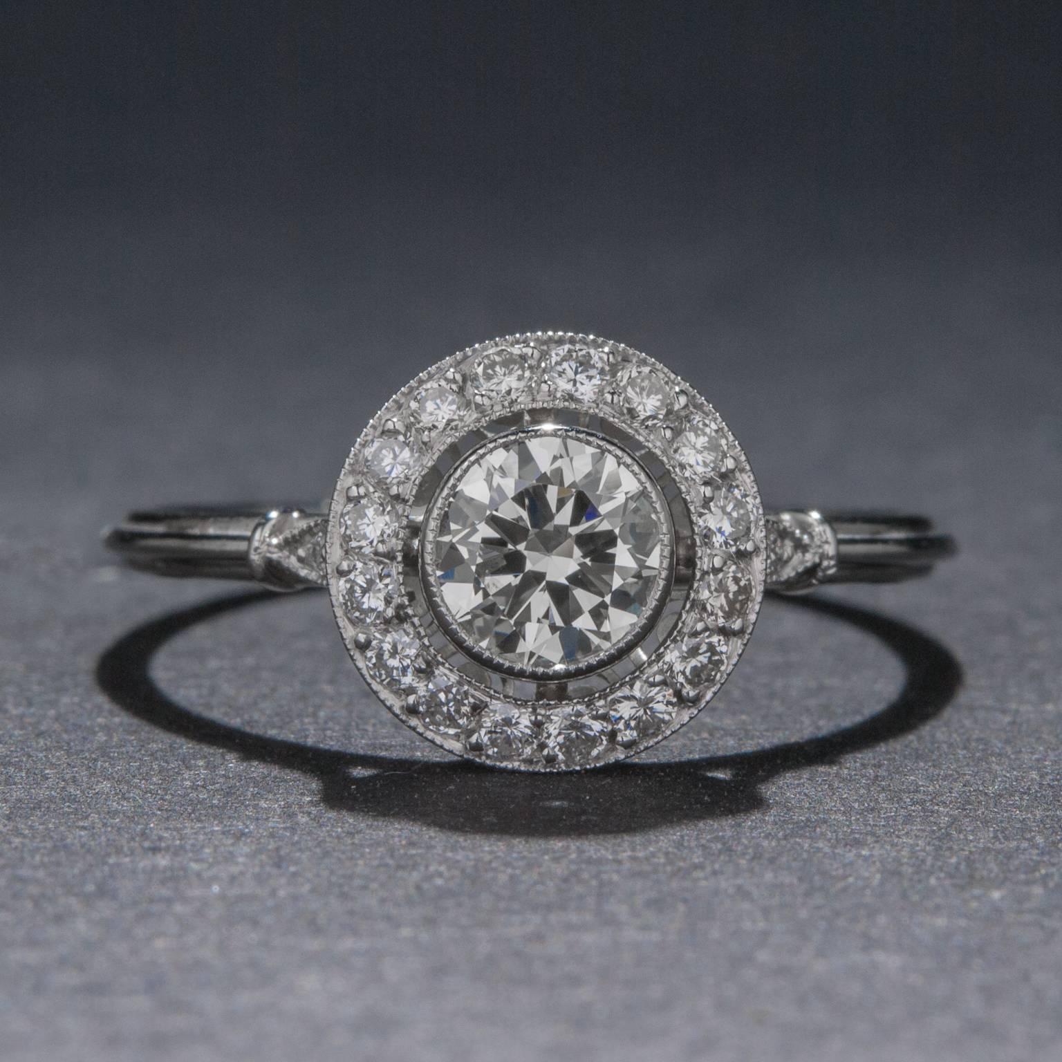 This lovely vintage style ring features a .51 carat center diamond which is surrounded by a halo of .18 total carats of accent diamonds. The ring is set in platinum and it is currently size 7.25.
