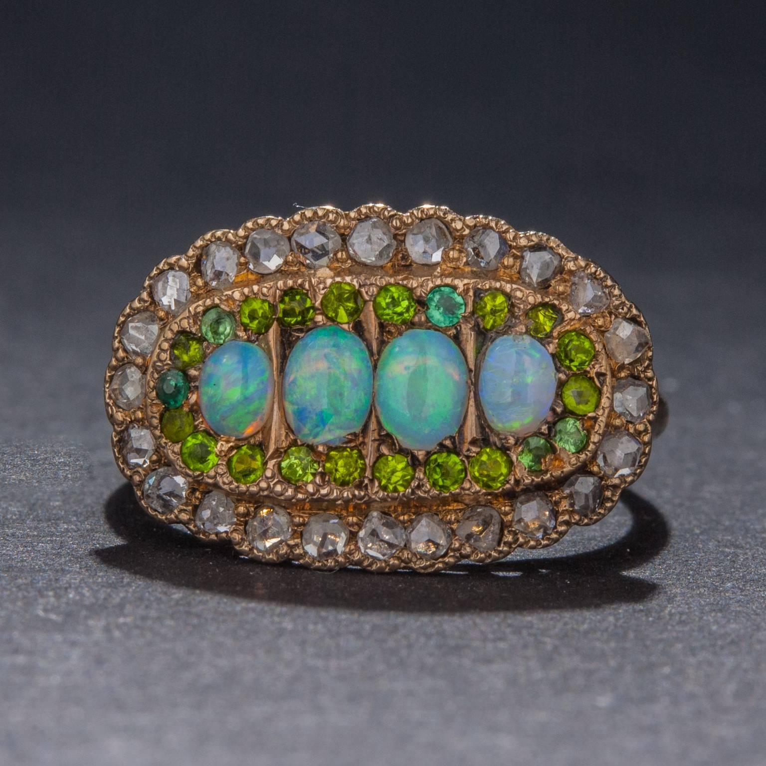 This exceedingly beautiful vintage ring was handcrafted in the Victorian era. The ring features 4 opals weighing a combined total of .50 carats, 24 diamonds for .50 total carats, and 22 demantoid garnet for a total of .25 carats. This rare ring is