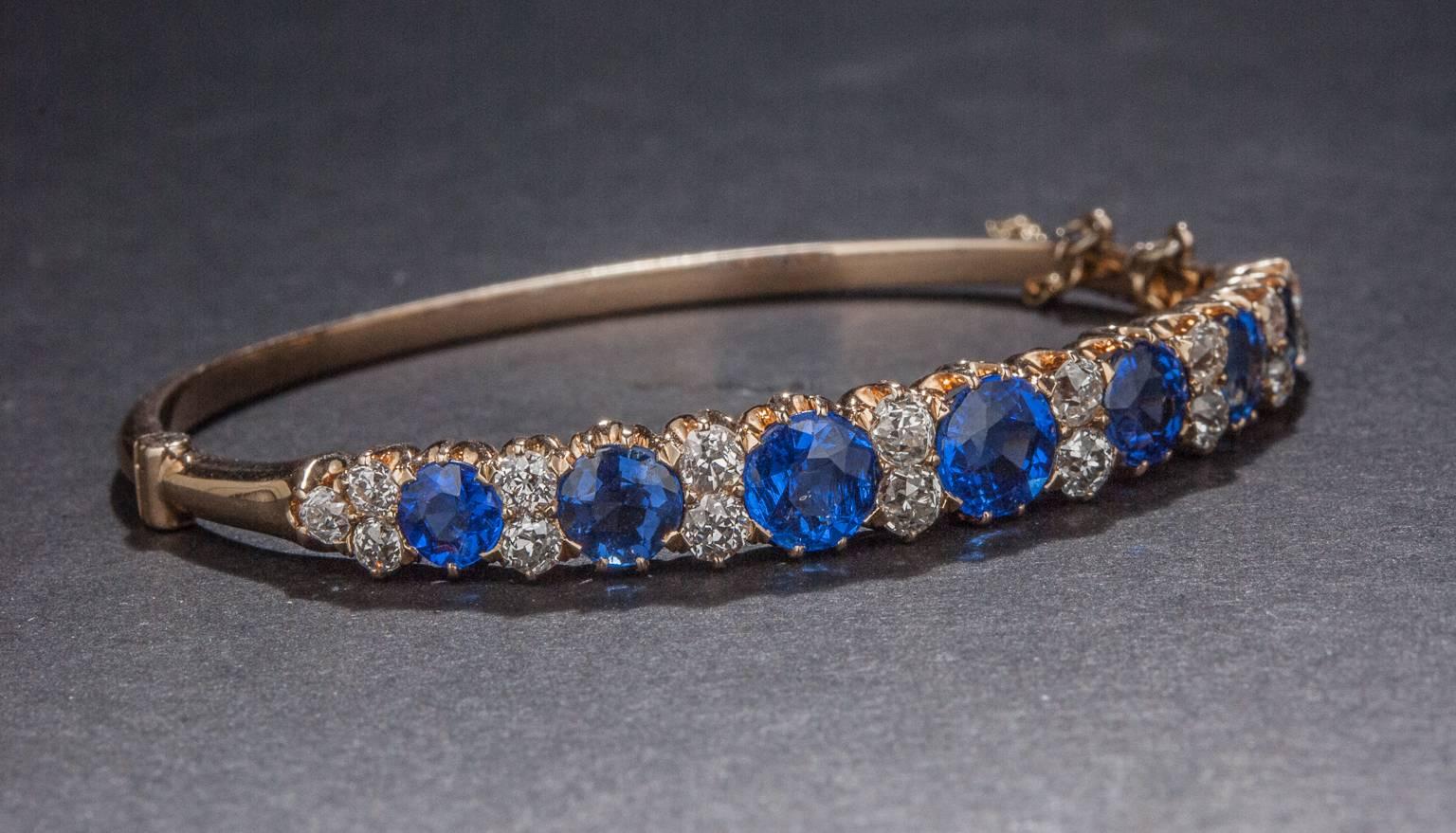 An exceptionally lovely bangle bracelet, crafted circa 1900s. This unique piece features 2.50 total carats of diamonds and 7 beautiful synthetic blue stones (which are original to the piece and to the era). This piece is made in 14k yellow gold.