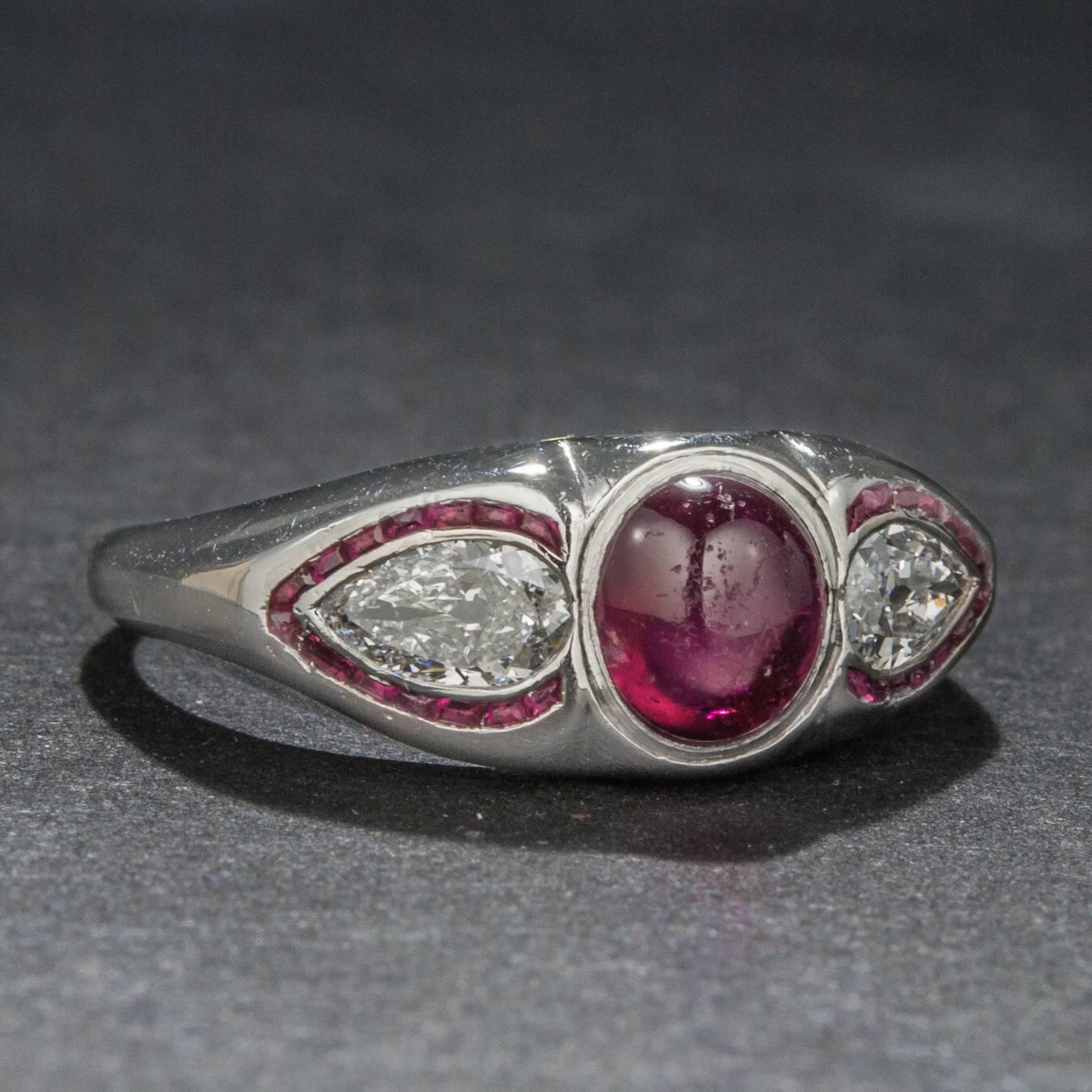This stunning Retro era ring includes a 1.25 carat cabochon cut ruby, two pear cut diamonds and additional ruby accents. The piece is crafted in platinum and is currently size 8.
