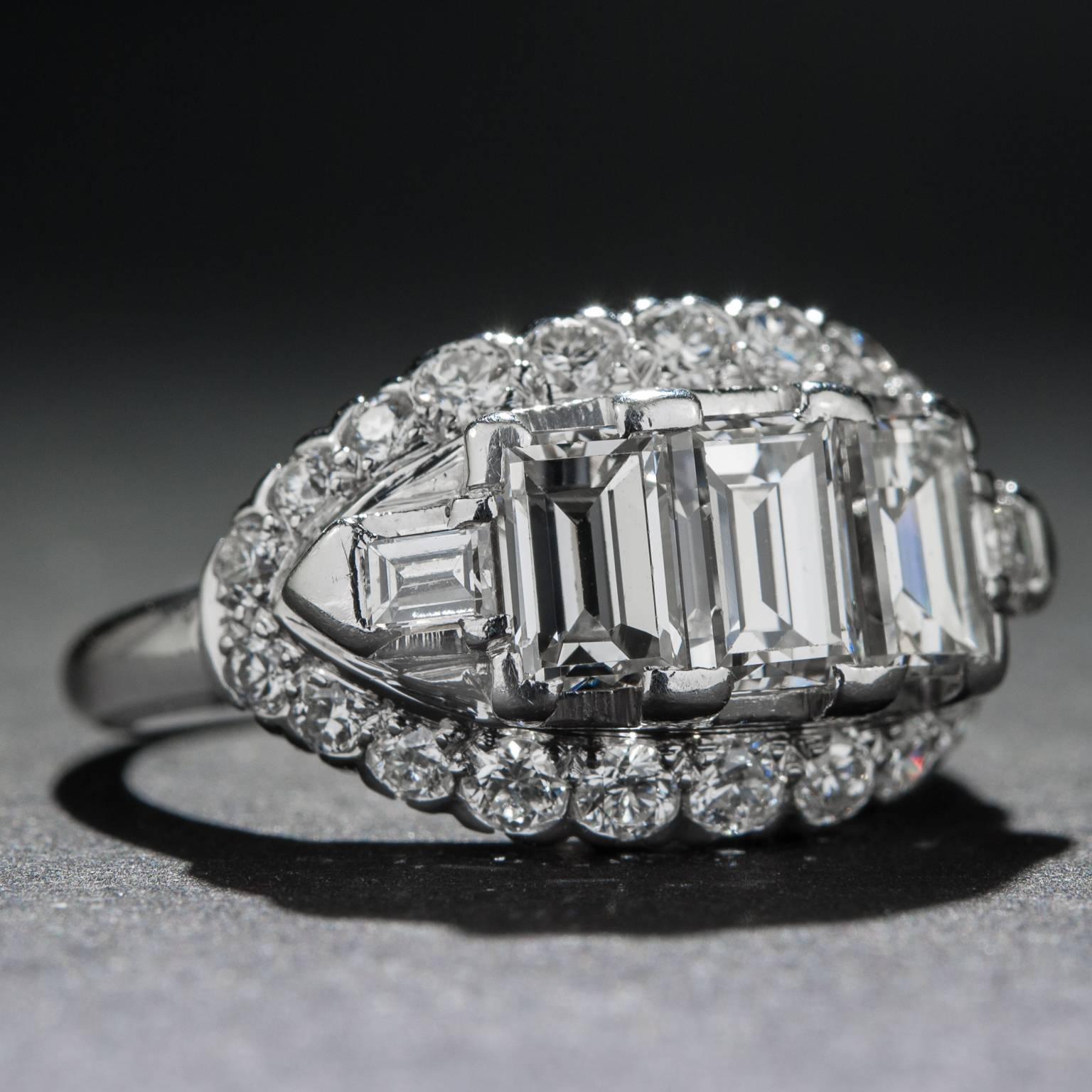 This stunning Art Deco ring features 3 gorgeous emerald cut diamonds for a total of 1.80 carats as well as an additional .70 carats of accent diamonds. This piece is crafted in platinum and it is currently size 7.25.