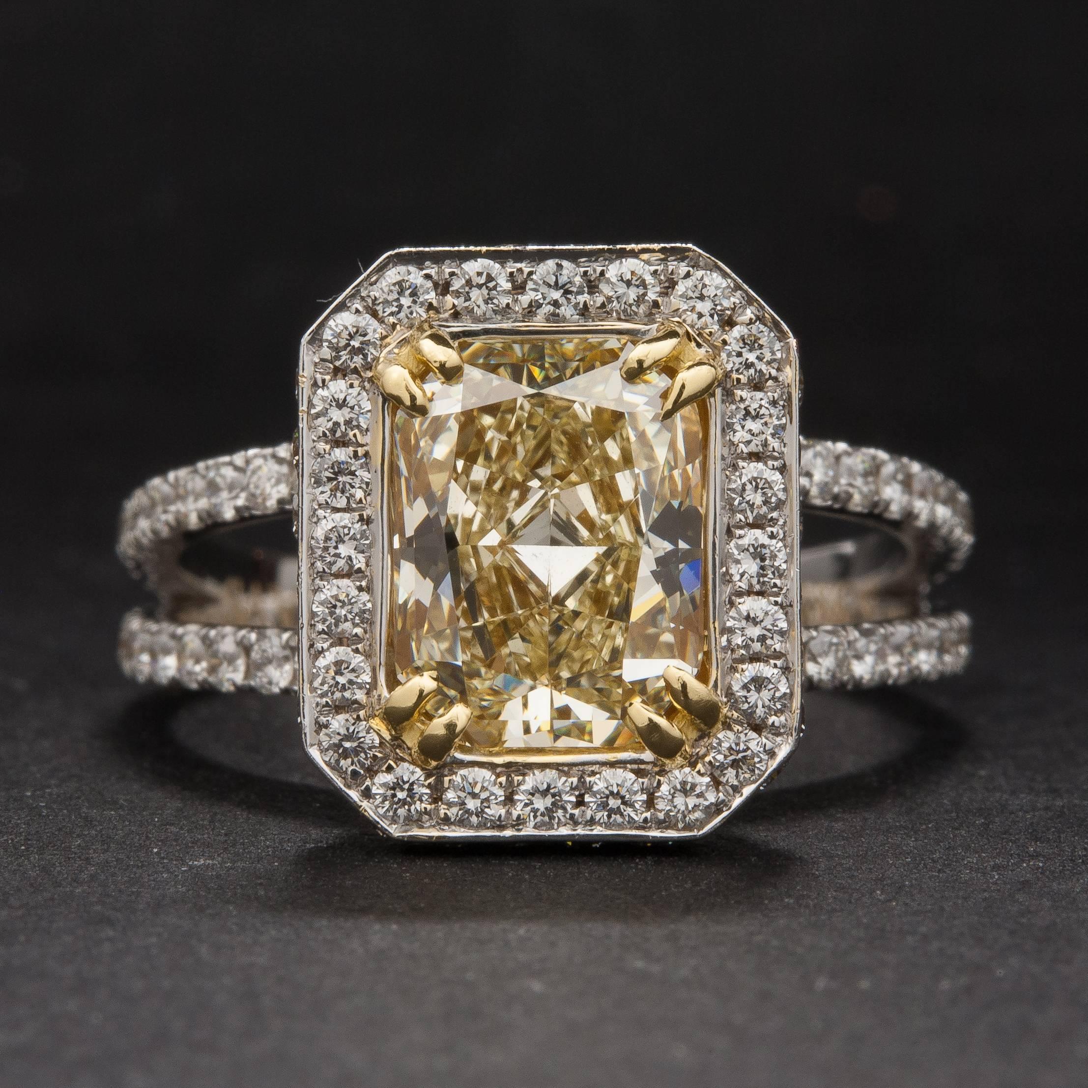 This extraordinary ring features a 2.02 carat radiant cut fancy yellow diamond (VS1 clarity) that is surrounded by 1.20 total carats of bright white diamonds. The beautiful split-shank mounting is crafted in 18k white gold and is currently size 7.
