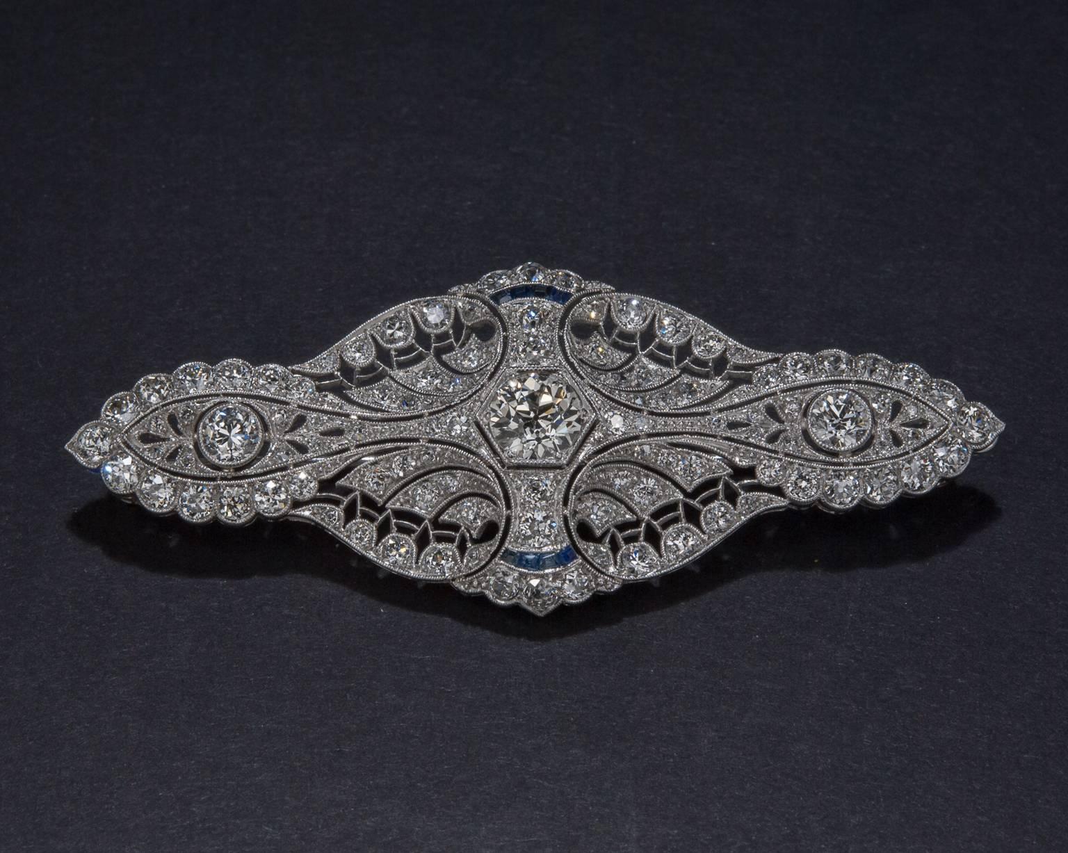 A gorgeous early Art Deco brooch with lots of sparkle. This piece features a .90 carat center diamond and sapphire accents. The brooch is handcrafted in platinum and it measures 2.5 inches across.