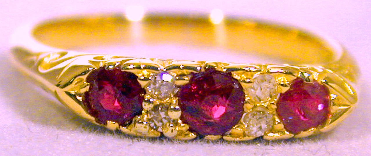 Lovely Victorian three stone ruby ring interspersed with four rose cut diamonds in an elaborately scrolled 18K gold setting. Wonderful to stack with other rings or wear alone. The ring is a size 8 1/4 and can be resized.