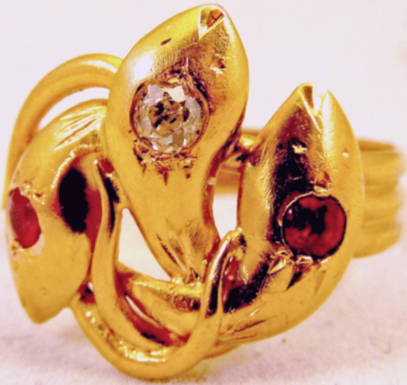 Dramatic Victorian triple headed snake ring set with 2 rubies and 1 diamond. The snake's tails travel around the ring and wrap around the snake's heads creating three rings in one. The ring is a size 12 and it's width is 3/4
