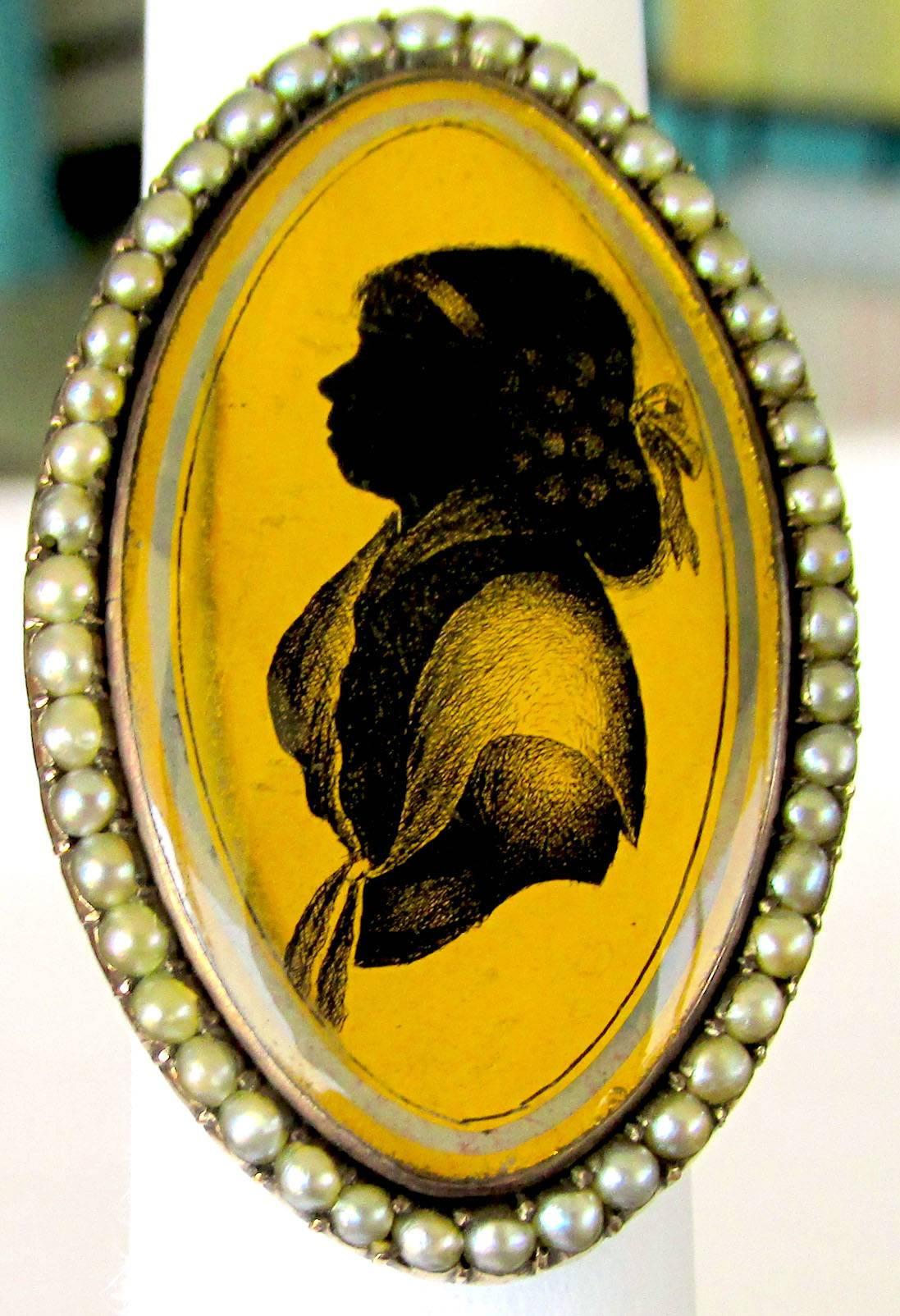 Exquisite Georgian verre églomisé, or gilded glass, portrait ring surrounded by seed pearls. Verre églomisé is a French term meaning gilded glass and is a decorative technique in which the back side of glass is gilded with gold leaf. The gilding