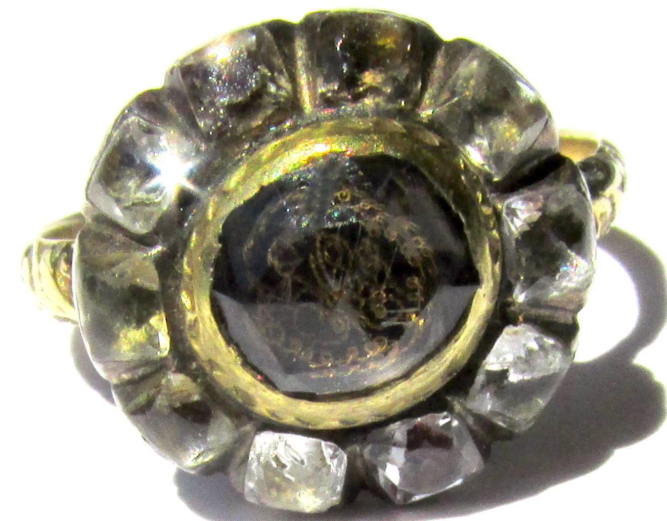 Seventeenth century Stuart crystal cluster ring surrounded by ten paste stones set in 18K gold and silver with embossed shoulders on the shank. The center carved rock crystal is mounted over a gold wire cipher placed on woven hair.
These rings were