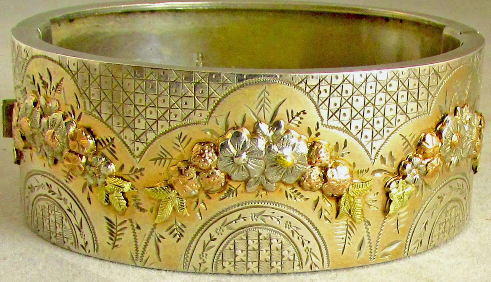 Exquisite Victorian silver bangle bracelet enhanced with a raised floral motif in two color gold. This unusual and striking cuff can be worn alone or joined with other gold or silver bangles. The bracelet measures 1 1/2