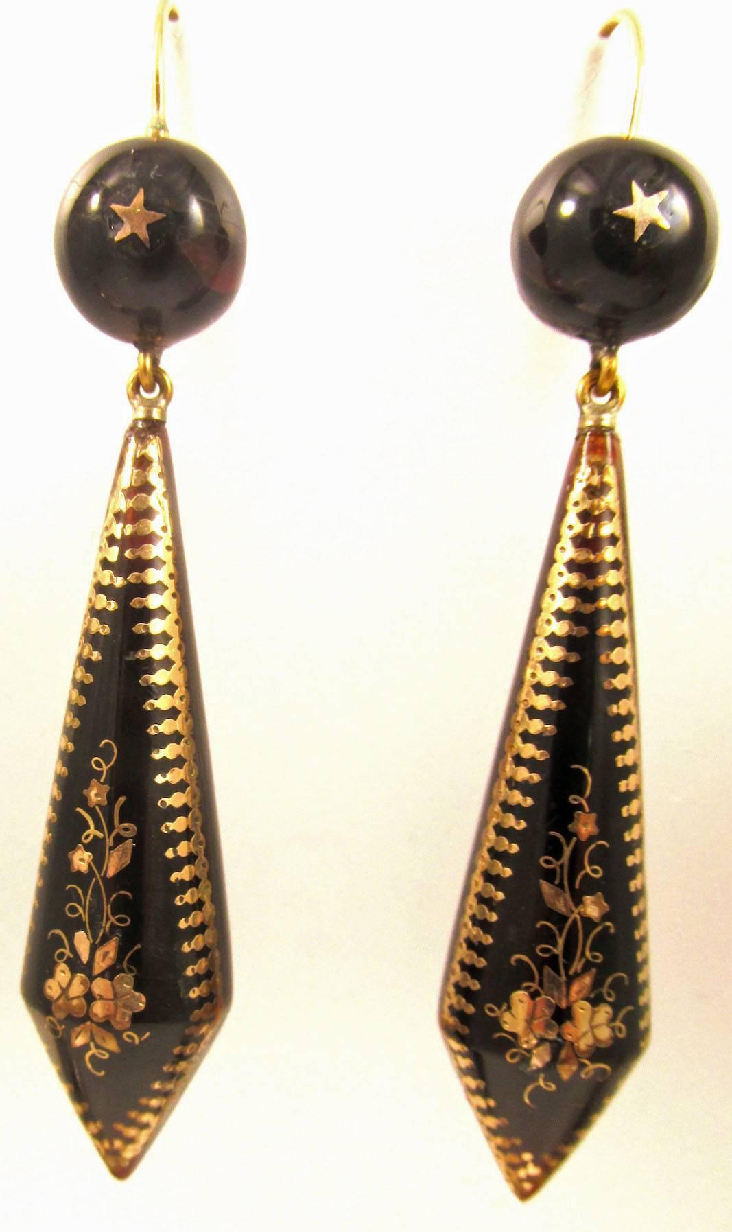 Dramatic Victorian long pique drop earrings set in gold with an intricate floral motif that is topped by a star.  The earrings measure 2 1/2" long by 1/2" at their widest. They date to the 1880"s.