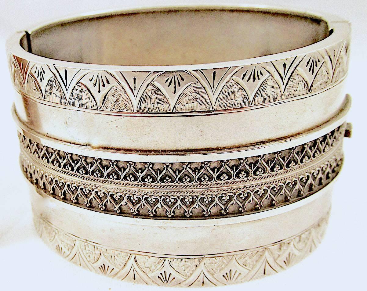 Elaborate sterling Victorian bangle bracelet decorated with arabesque designs in its center and engraved arches on its edges. This bold cuff measures 1 1/2 inches wide, it's interior dimensions are 2 x 2 1/8 inches. Striking enough to wear alone or