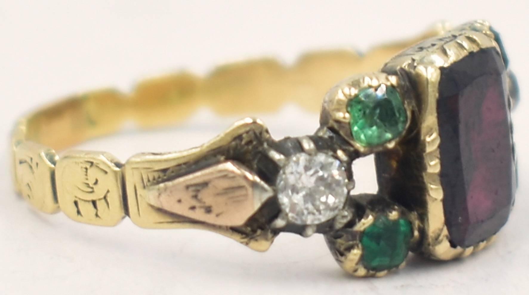 Delightful Georgian multi-stone ring with a large garnet in the center, two emeralds on each side with a diamond attaching each of them to the beautifully engraved 15K gold band on either end. Completely described in one sentence! What more can I