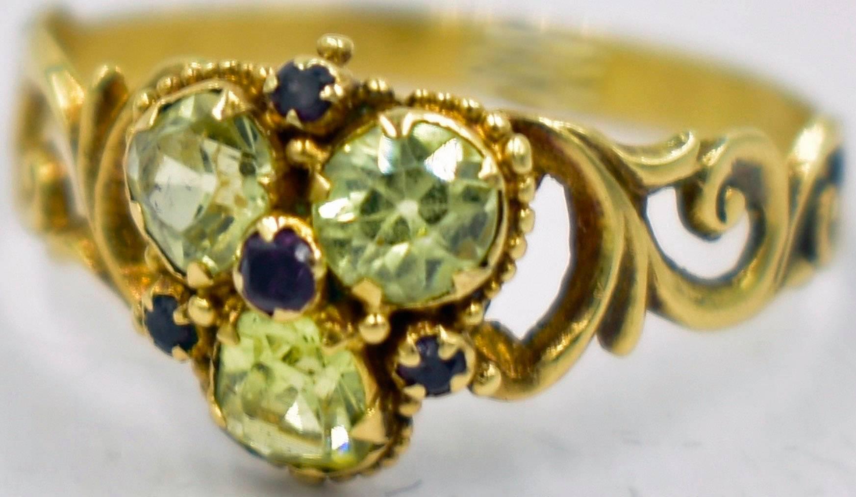 Sparkling Georgian chrysoberyl ring with four small garnets highlighting the design. The stones are in a beautiful swirling setting of 15K gold. The back of the band is decorated with an engraved floral and leaf design. The ring is a size 6 1/2 and