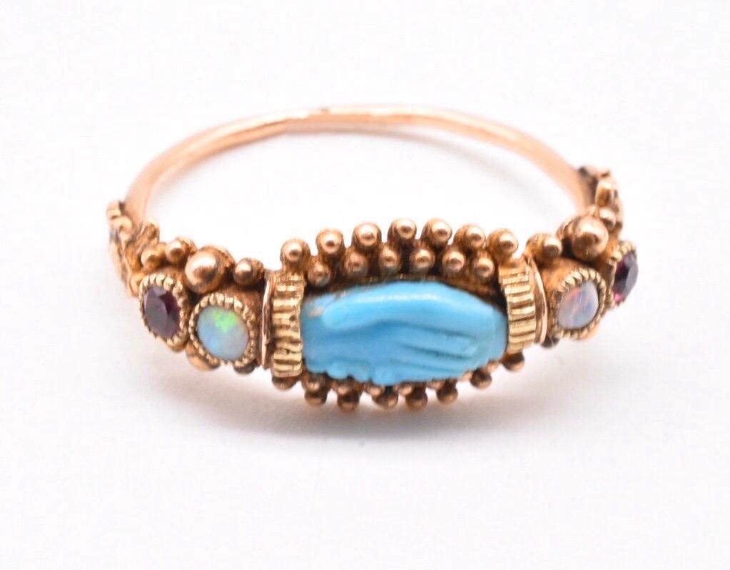 Georgian 18K gold cannetille work ring set with a carved turquoise in the shape of a pair of clasped hands, a symbol of friendship. On either side there are set an opal and a garnet. This is truly an unusual and rare ring. It is a size 7 and