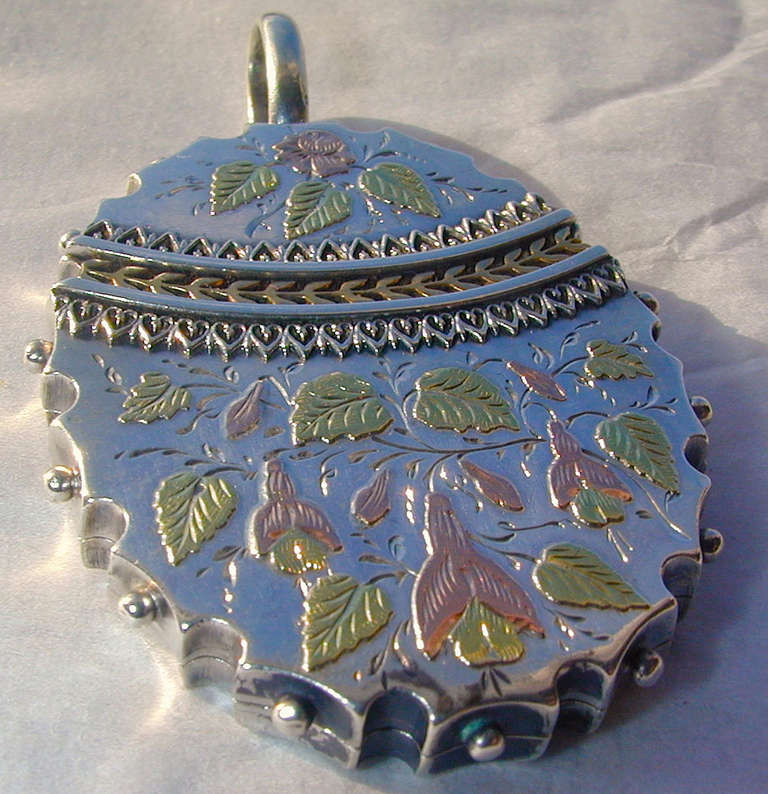 Victorian silver and three color gold locket with a raised floral and foliate design. Wonderful to wear on a chain, either short or long as shown here. The locket measures 1 3/4