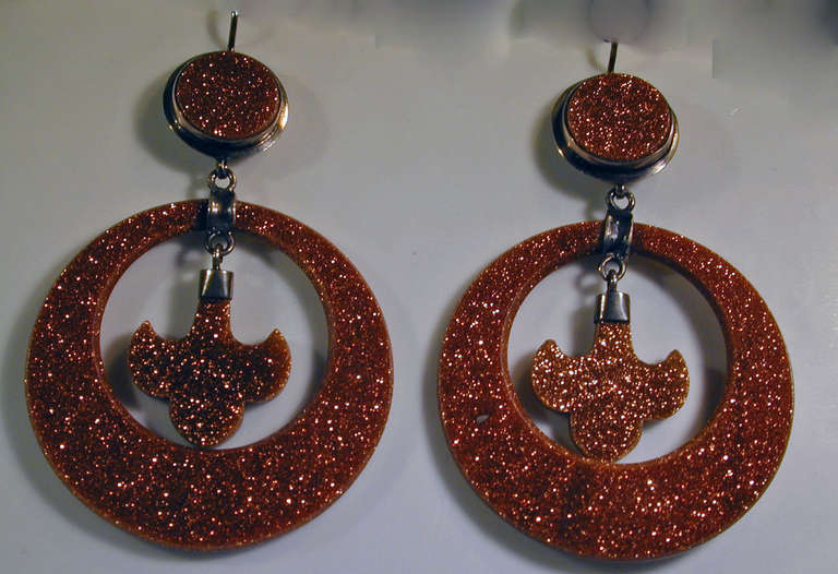 Sparkling Victorian hoop earrings of goldstone set in silver. A delightful fleur de lis hangs in the hoop. Goldstone was invented in the 17th century in Italy. It is also called aventurine glass. The earrings measure 2 1/4