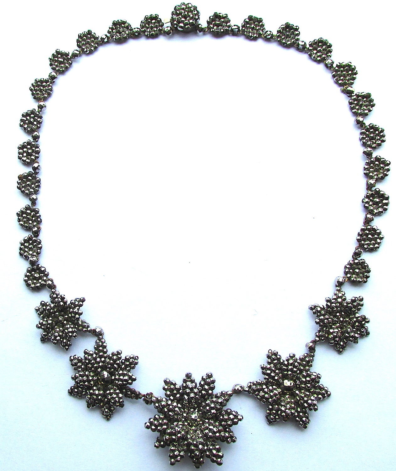 Elegant Victorian cut steel necklace with a floral motif of large multi-petaled flowers. Lovely to wear on elegant occasions as well on daily trips around town. The necklace is 17 3/4" long and measures 1" at its widest point. Cut steel