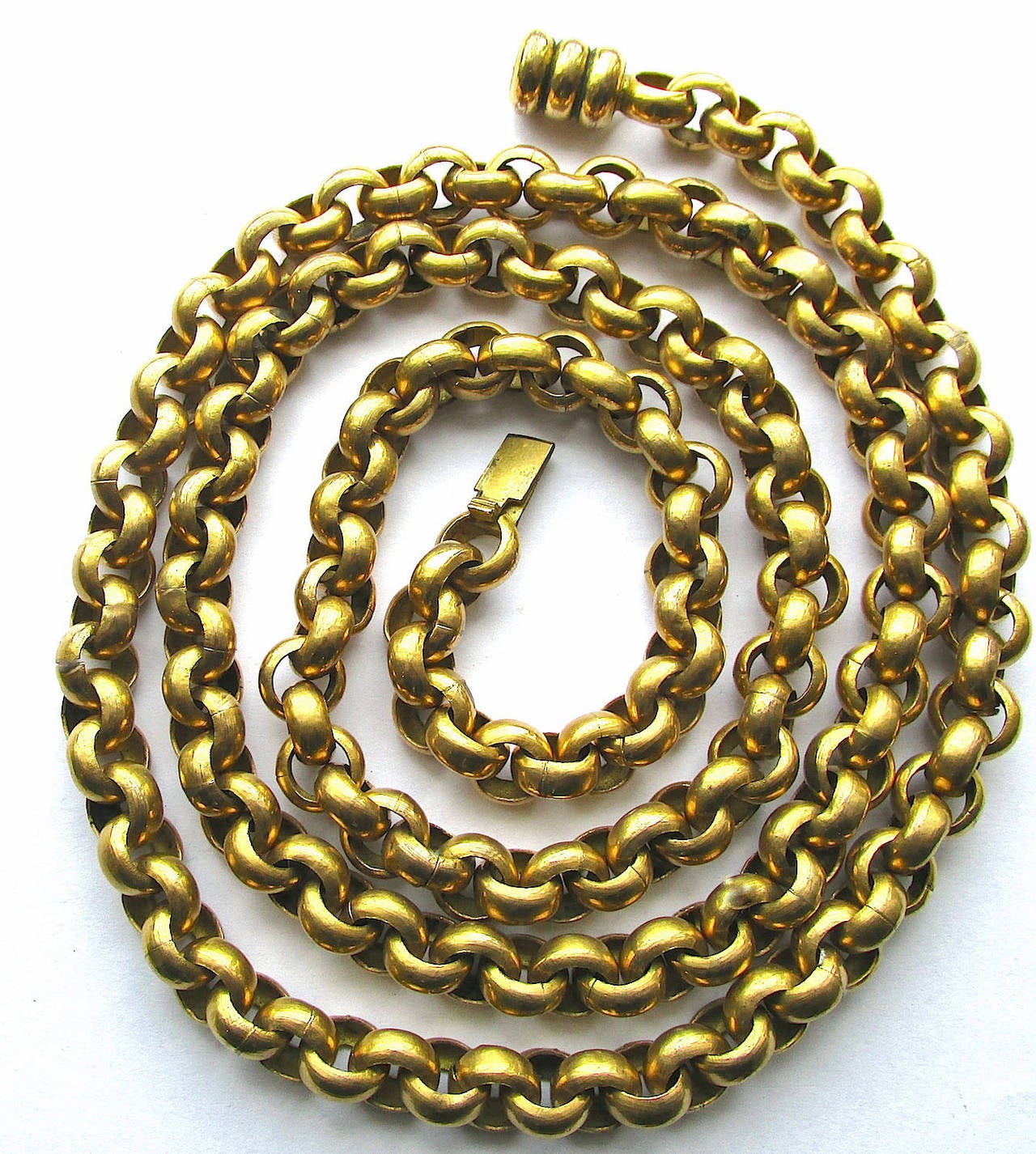 Bold Georgian pinchbeck long chain with a barrel clasp was used in its day to hold ones muff. Today one wears it for glamor. It can be triple looped to wear high or doubled to wear long. It is versatile for day or evening wear. Pinchbeck is an alloy