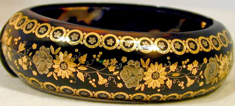 Victorian pique bangle beautifully decorated with an ornate floral motif. Bracelets of this type are rarely found. Pique work, tortoiseshell inlaid with gold and silver, was brought to England by the Huguenots who fled religious persecution by the