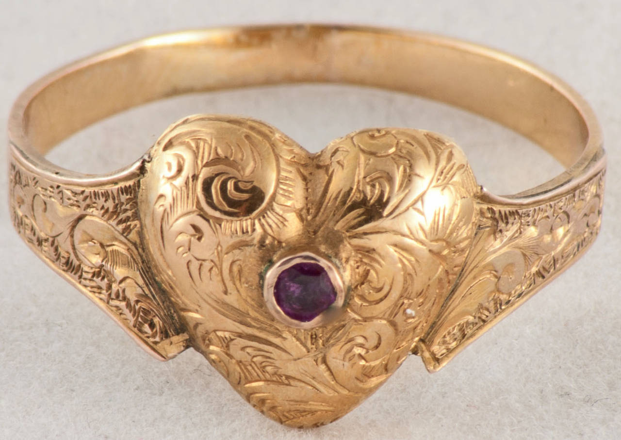 Romantic 15K gold heart ring beautifully engraved and set with a ruby. The ring is size 9 1/4 and can be sized to fit.