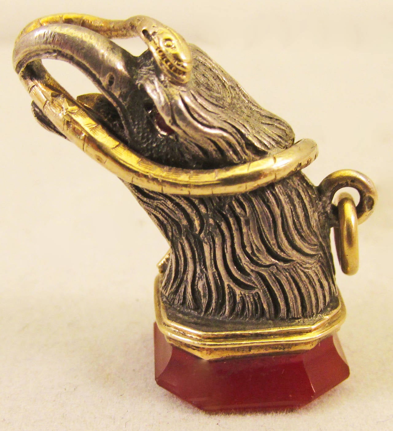 Dramatic Georgian fob of a silver eagle's head with garnet eyes carrying a gold snake resting on a carnelian seal. Perfect on a watch chain or a necklace or a charm bracelet. The fob measures 1 1/8