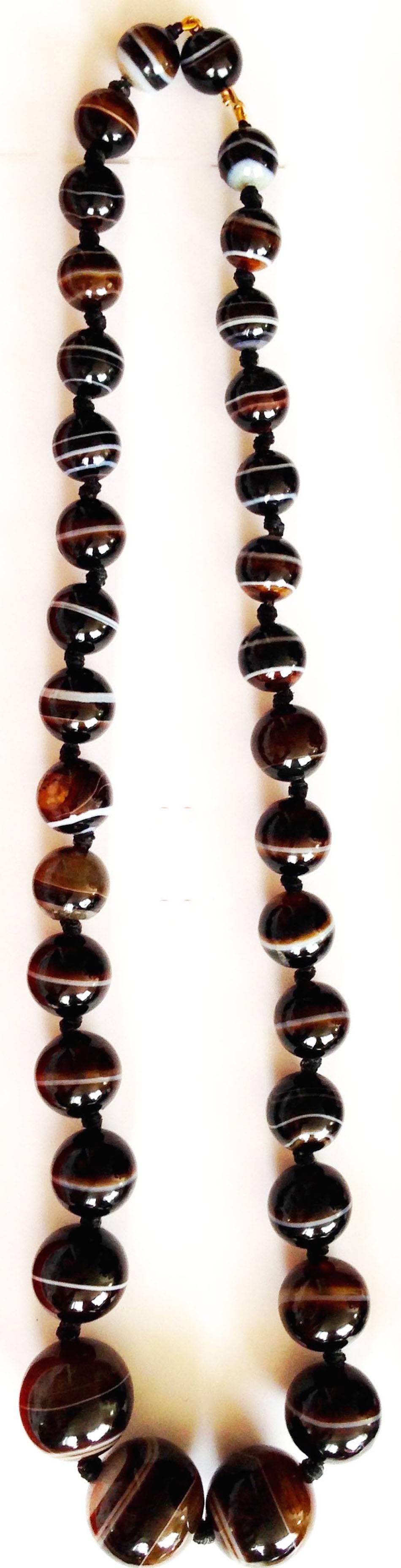 Bold Victorian banded agate bead necklace with three large beads tapering down to smaller ones. There are 34 beads in the necklace which has a bead clasp. Agate beads have become very collectible as many believe they have mystical qualities. The