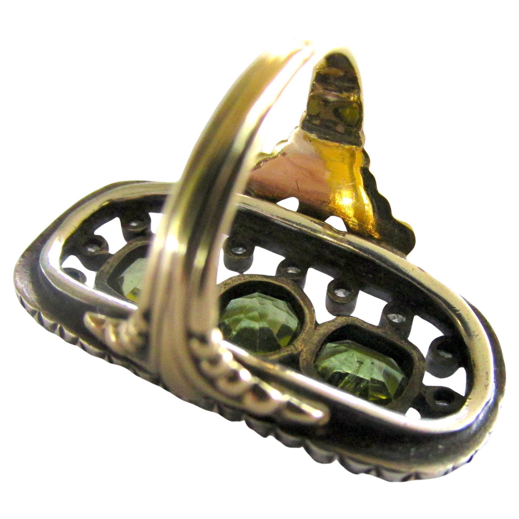 Bold mid 19th century peridot and rose diamond ring set in 18K gold and silver with an ornate shank. Peridots are prized for their yellow greenish color. The ancient Egyptians mined peridot on the Red Sea island of Zabargad, the source for many