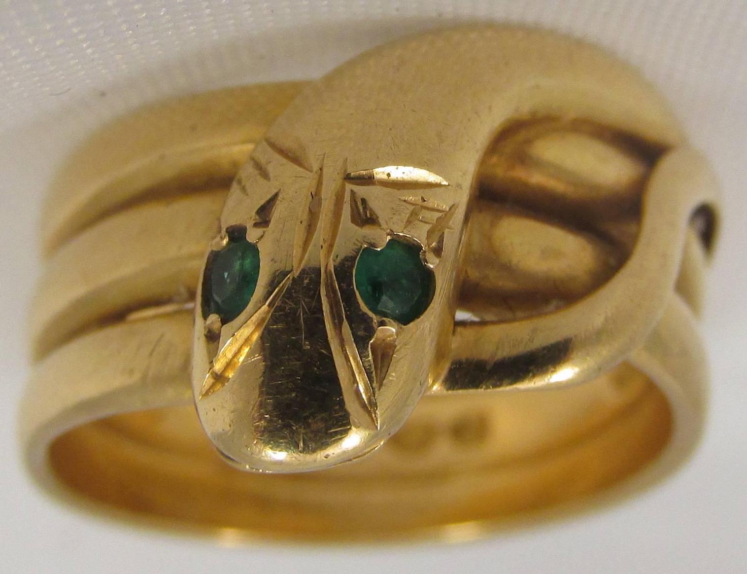 Striking 18K snake ring with emerald eyes. Snakes represent fertility and the creative life force. They are symbols of rebirth, transformation, immortality, and healing. This snake ring is a size 8 1/4 and is 3/8" wide. Its hallmarked date is