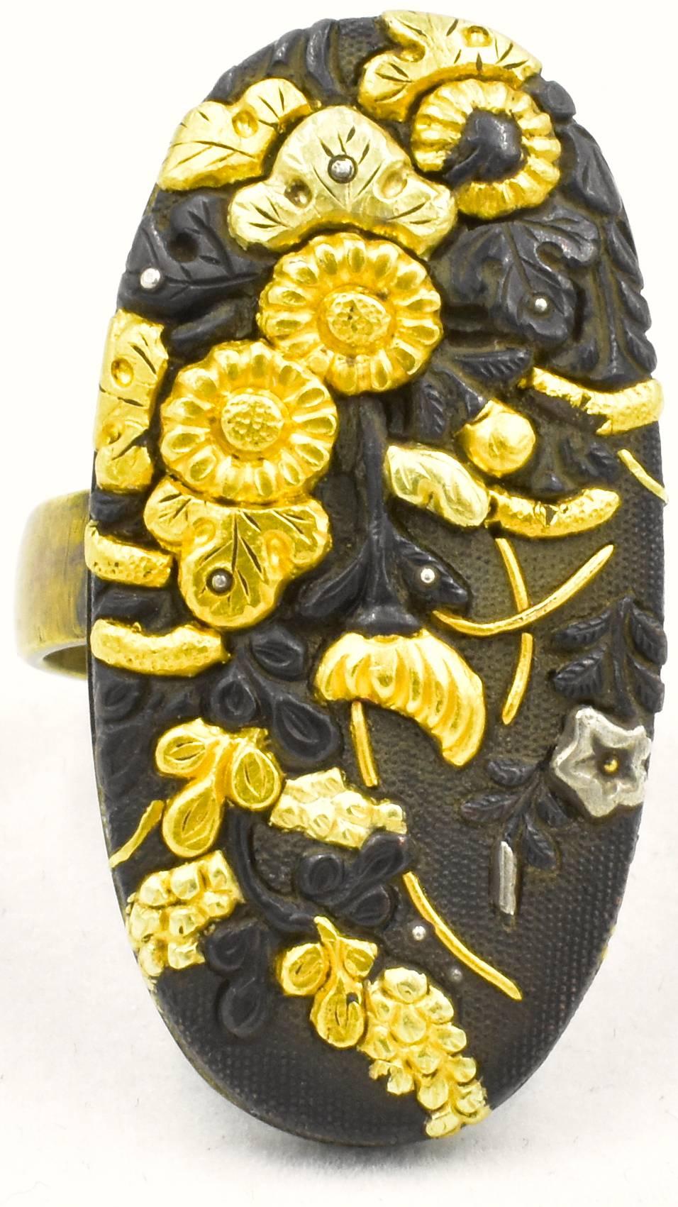 Marvelous shakudo ring decorated with a bold floral motif in gold and silver was made in Japan in the 1890's. Shakudo was made in Japan during the Samurai period by artisans who made ornaments to adorn swords and other weapons. It became popular to