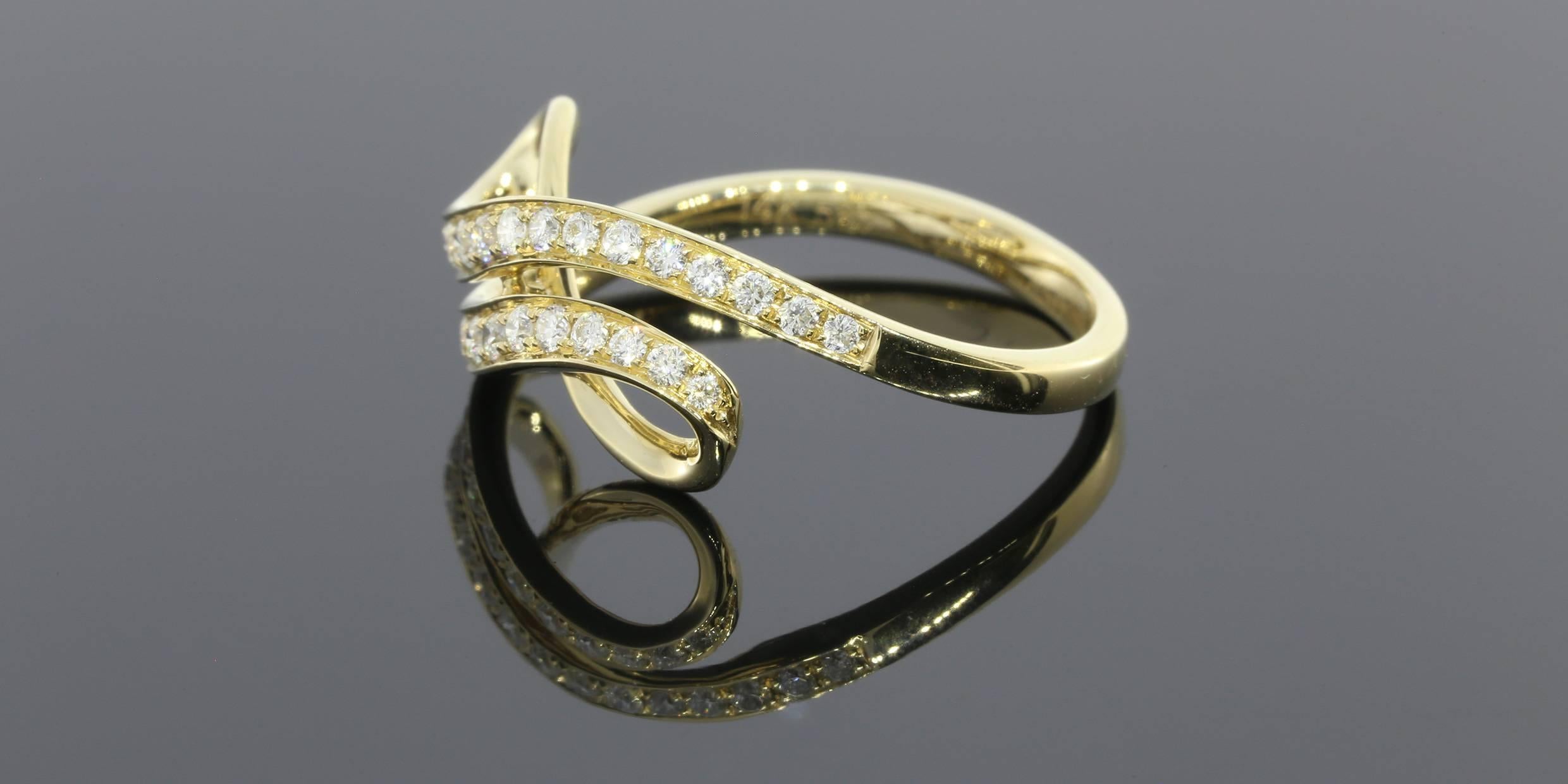 This yellow gold right hand ring has a unique bypass swirl design that resembles an infinity symbol. It is set with round brilliant diamonds with a total carat weight of .36CTW. The ring is 14K yellow gold with a bright finish.  This ring is a size