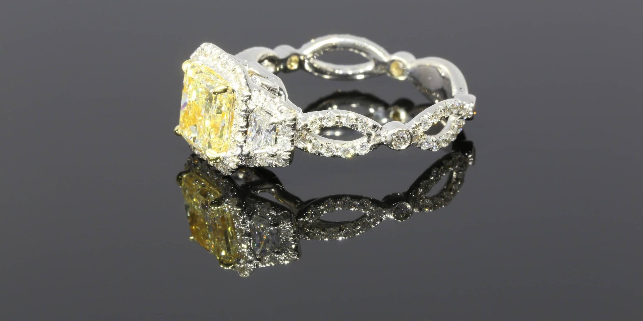 This engagement ring is one of a kind! It features a fancy light yellow radiant shaped center diamond with a total carat weight of 1.57CT and a clarity of SI1. It is flanked by two trapezoid shaped side diamonds. Both the center diamond and the