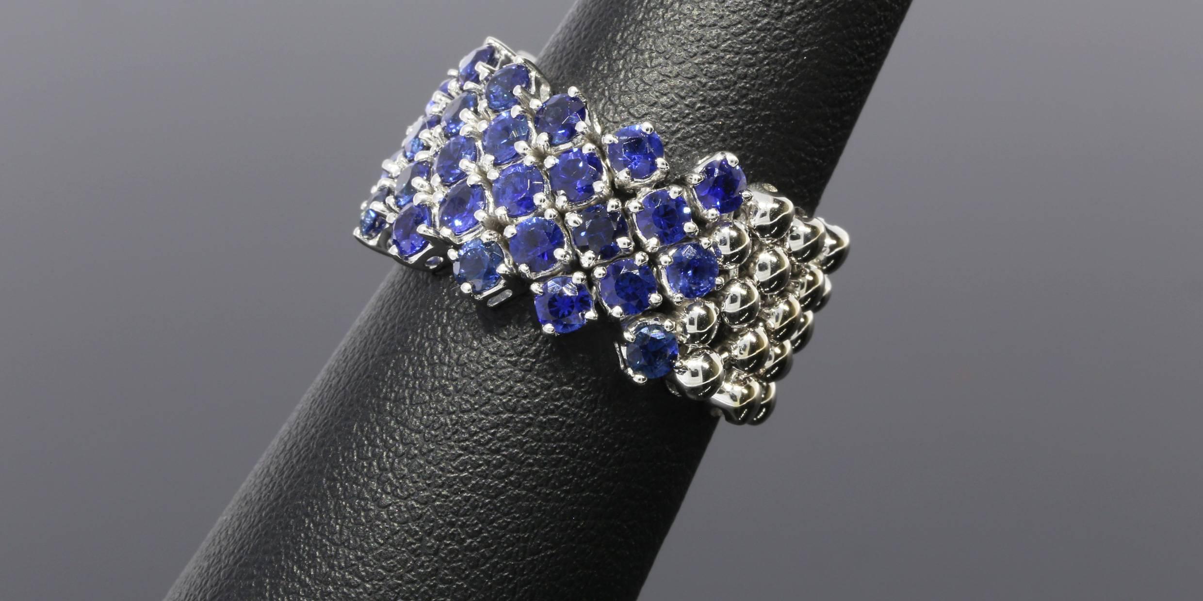 This beautiful & unique band is an 18 karat white gold sapphire flexible band ring. The ring has 33 natural, round, blue sapphires that have a combined total weight of 3 carats. The sapphires are prong set, & the mesh style ring is flexible except