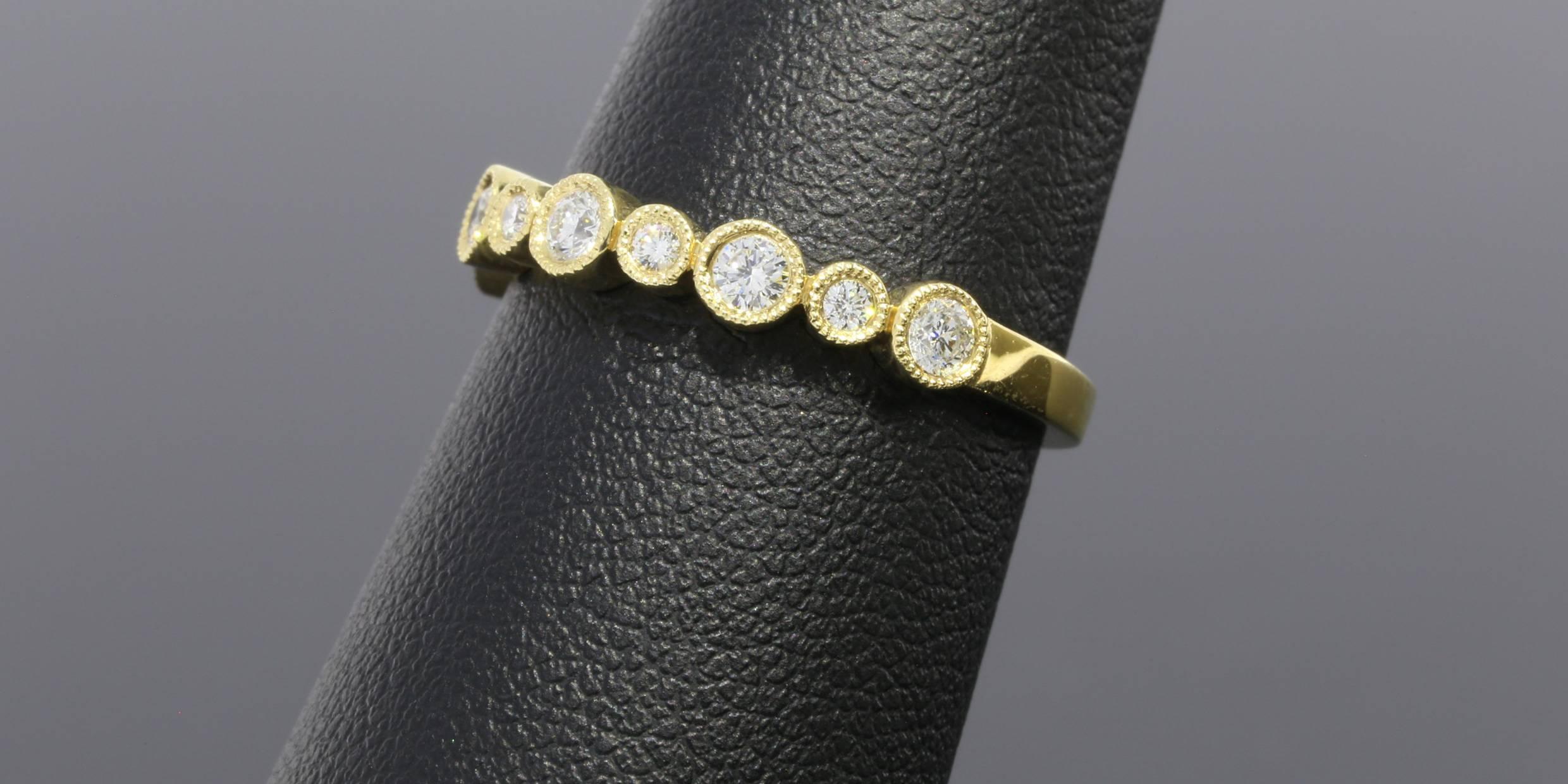 This classic band is a beautiful 14 karat yellow gold diamond band that can dress up any ring. It can be used as a wedding band, stand alone band, or stack ring. The ring has 9 round brilliant cut diamonds that have a combined total weight of .32