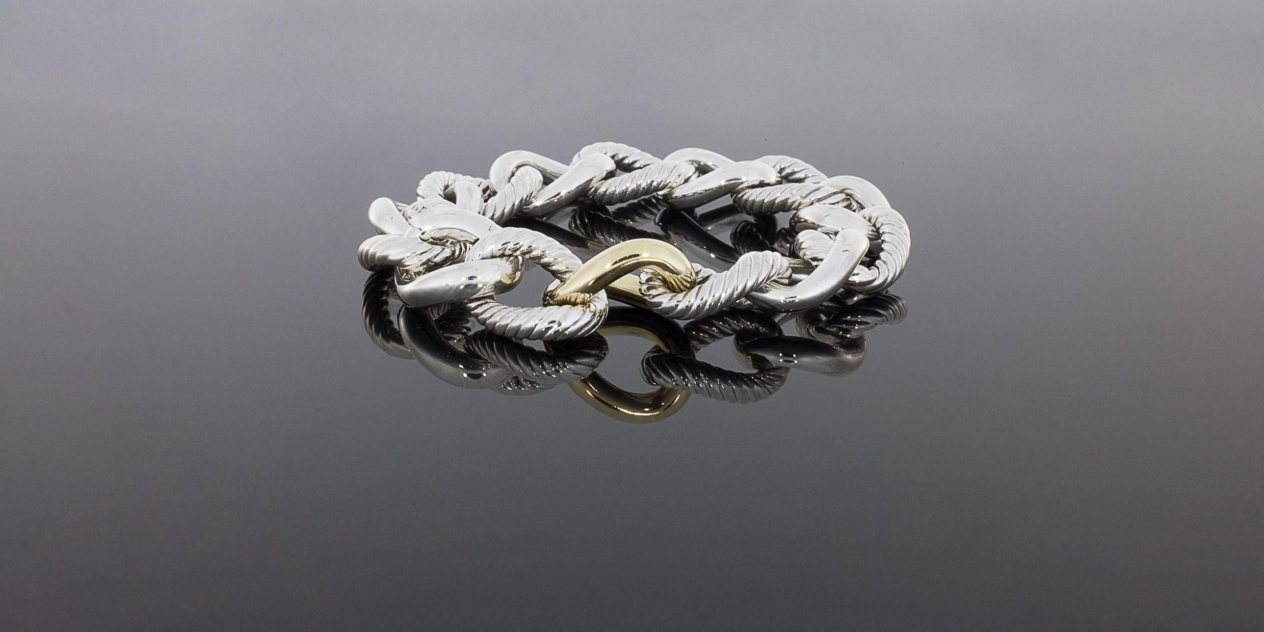 David Yurman's cable style jewelry has become his signature, the unifying element of every collection. This classic bracelet from the Belmont collection features 18 millimeter wide, curb style, sterling silver links with an 18 karat yellow gold foca
