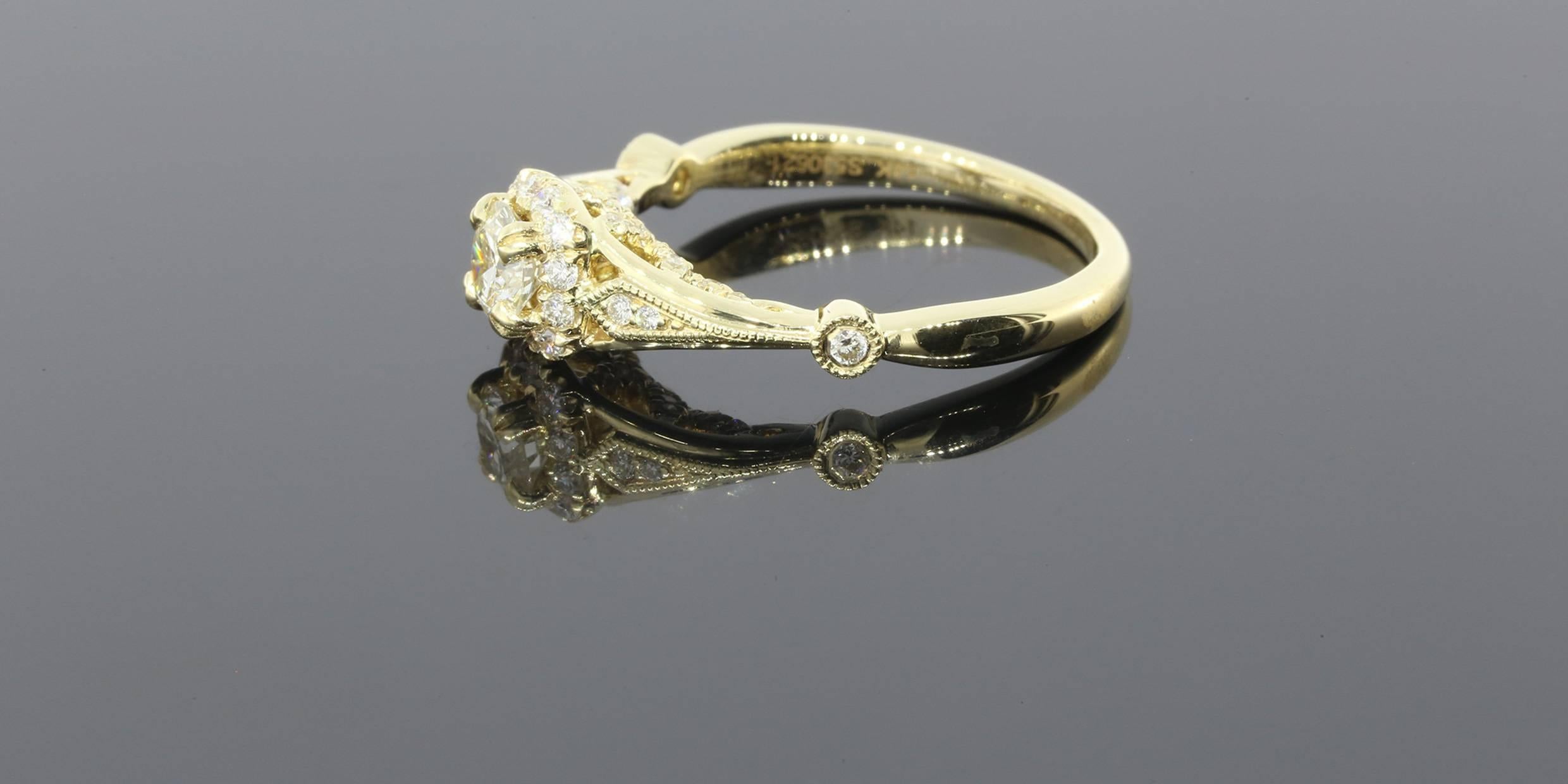This beautiful yellow gold engagement ring has lovely, intricate, vintage inspired details all over. The center diamond is a .36 carat round brilliant cut that is J/SI1 in quality. It is split prong set & surrounded by a halo of prong set