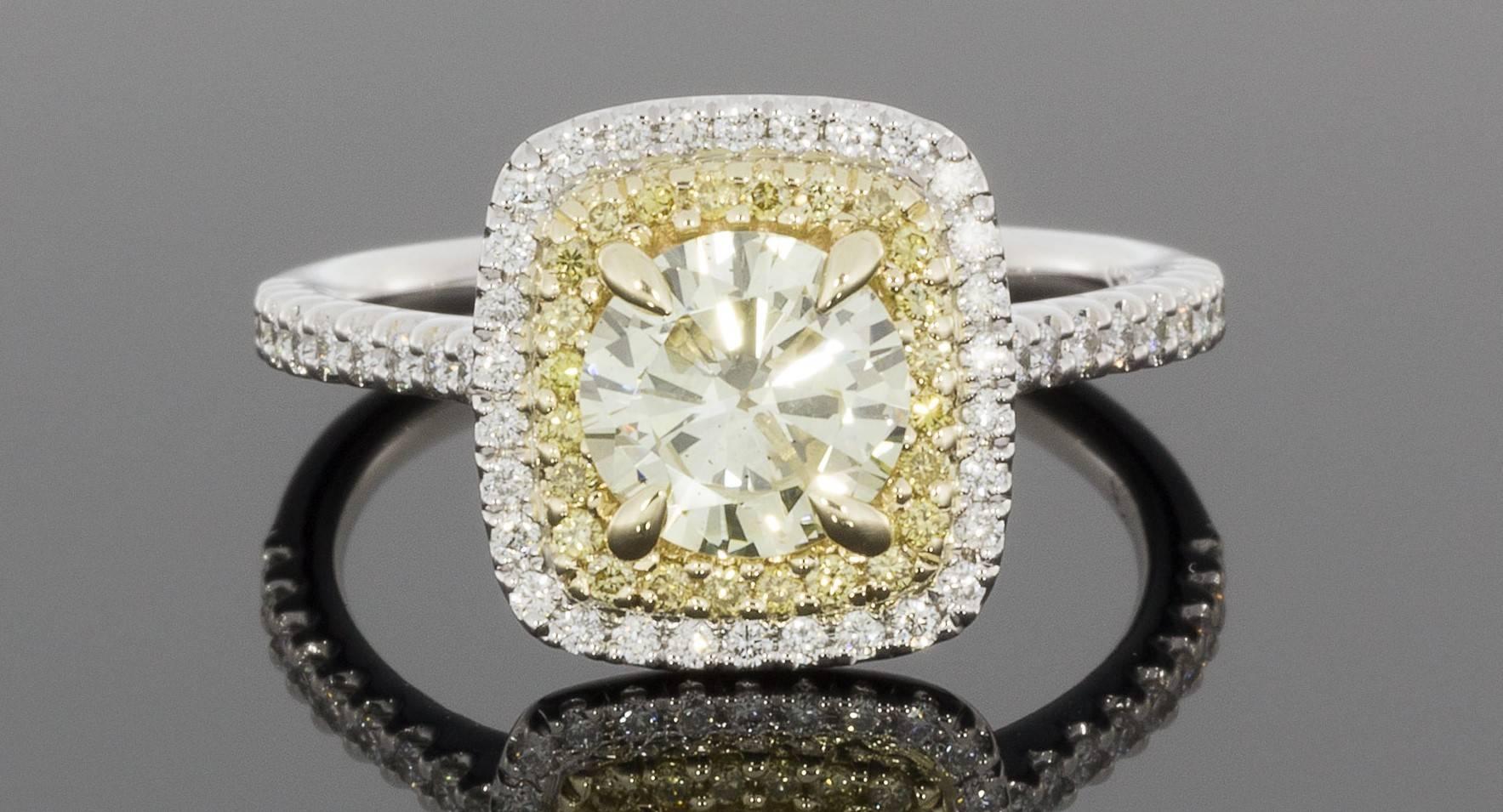 This gorgeous halo engagement ring features a stunning 1.03 carat, canary yellow, round brilliant cut center diamond that is prong set in a yellow gold head on a custom made ring. This center diamond grades as Fancy Light Yellow in color, is very