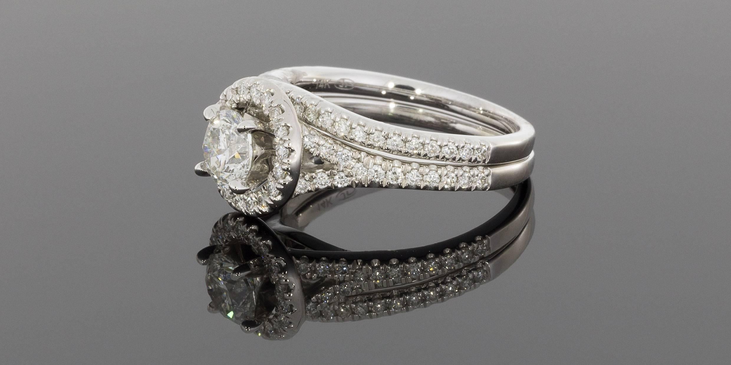 This stunning wedding set has a combined total weight of 1.27 carats and features a gorgeous halo diamond engagement ring and matching curved diamond wedding band. Both rings are comprised of 14 karat white gold.

The engagement ring has a .70 carat