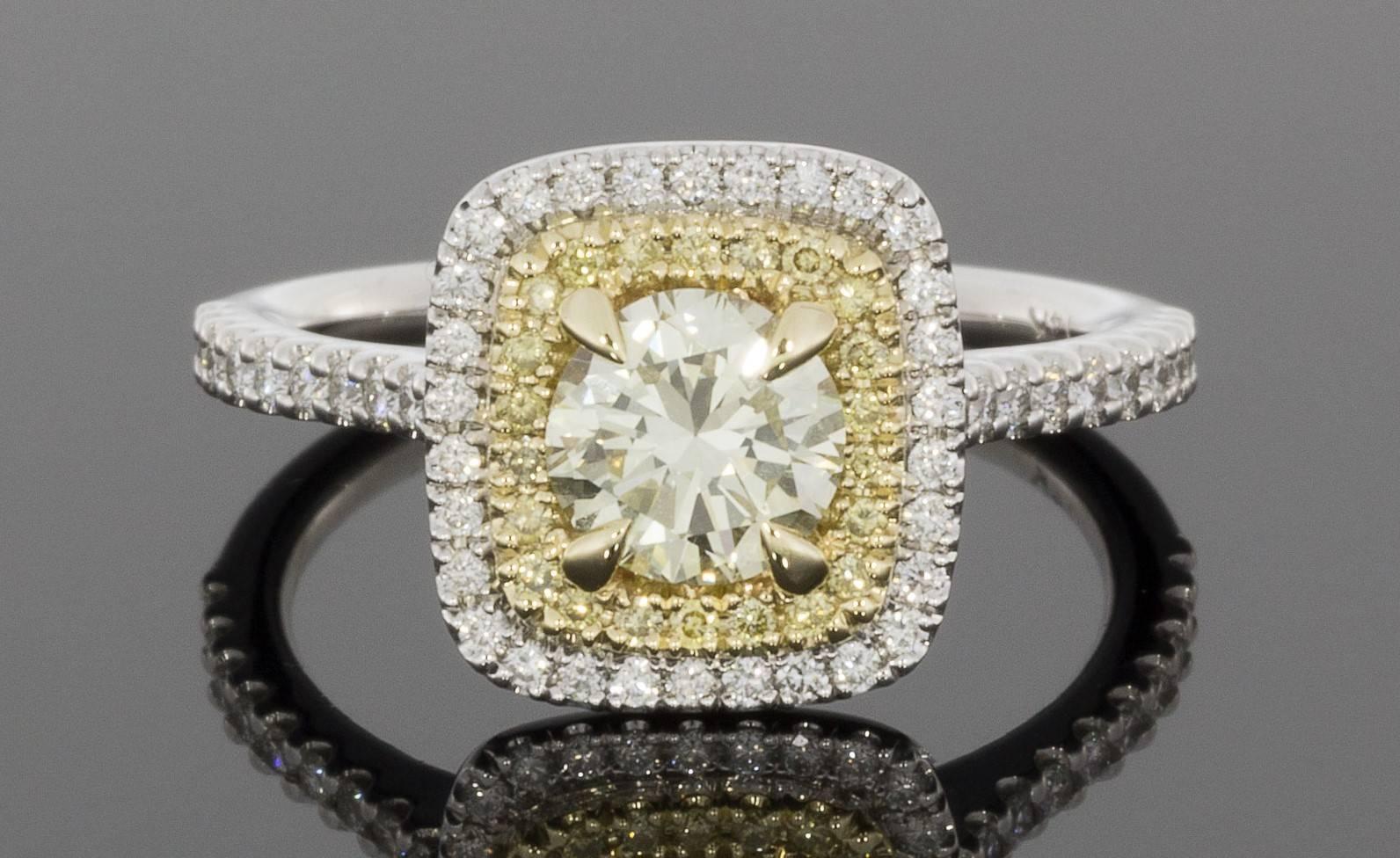 This gorgeous halo engagement ring features a stunning .74 carat, canary yellow, round brilliant cut center diamond that is prong set in a yellow gold head on a custom made ring. This center diamond grades as Fancy Light Yellow in color, is very