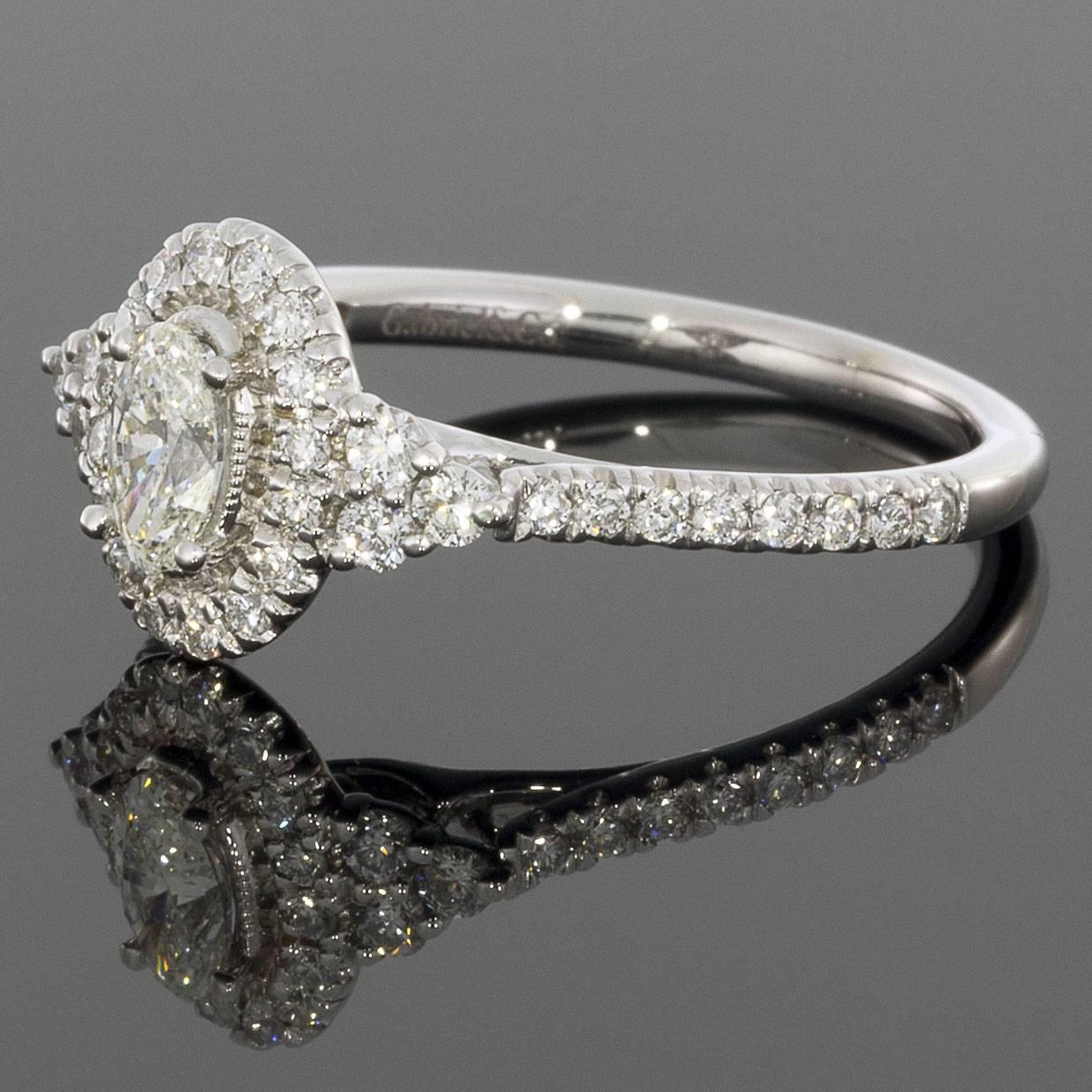 An oval cut center diamond with a complementary halo is framed on either side by a cluster of three round diamonds in this beautiful ring by Gabriel & Co. Pave diamonds along the band provide the finishing touch to this white gold engagement