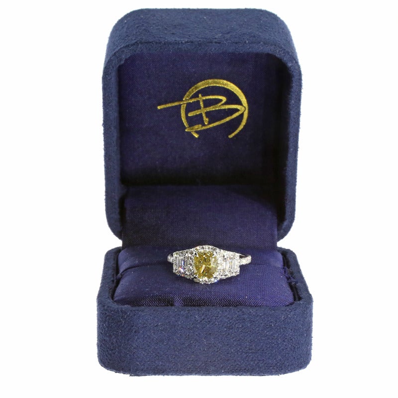 This engagement ring is custom made & one of a kind! It features a champagne color, cushion shaped center diamond with a carat weight of 1.13 carat and a clarity of SI2. It is flanked by two trapezoid shaped side diamonds. Both the center diamond