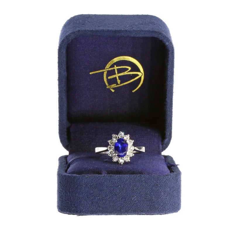 The ring features one oval brilliant cut natural blue sapphire weighing 1.36CT. The ring also features round brilliant cut white diamonds weighing 0.65CTW. The diamonds are G/SI1 in quality. The diamonds are prong set in a round halo that is based