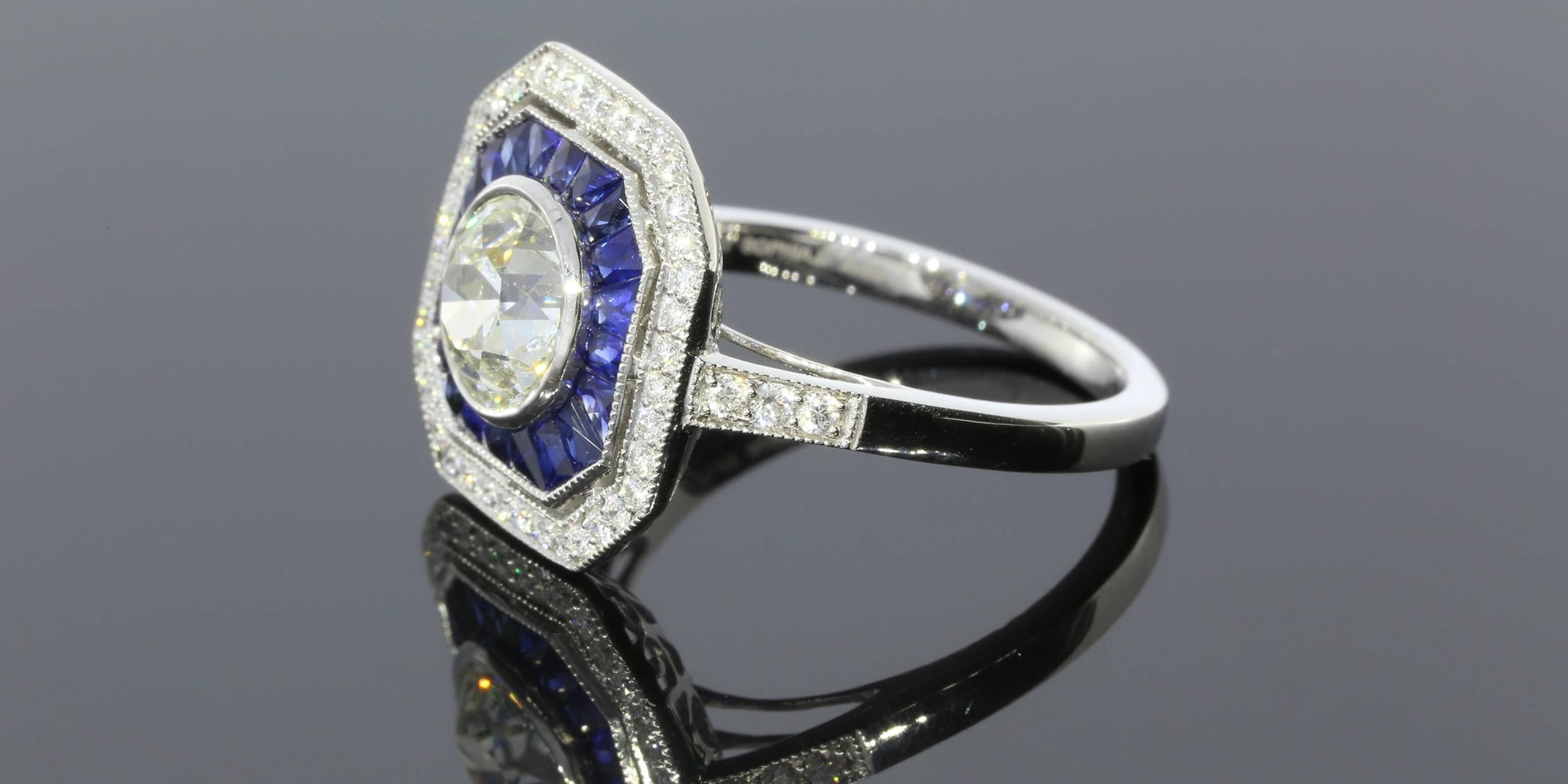 This mesmerizing ring features one Old European cut center diamond weighing 1.43 carats. The diamond is graded as K/VS1 and is bezel set. The ring also features 0.29CTW round brilliant cut diamonds and 0.75CTW of natural blue sapphires that were
