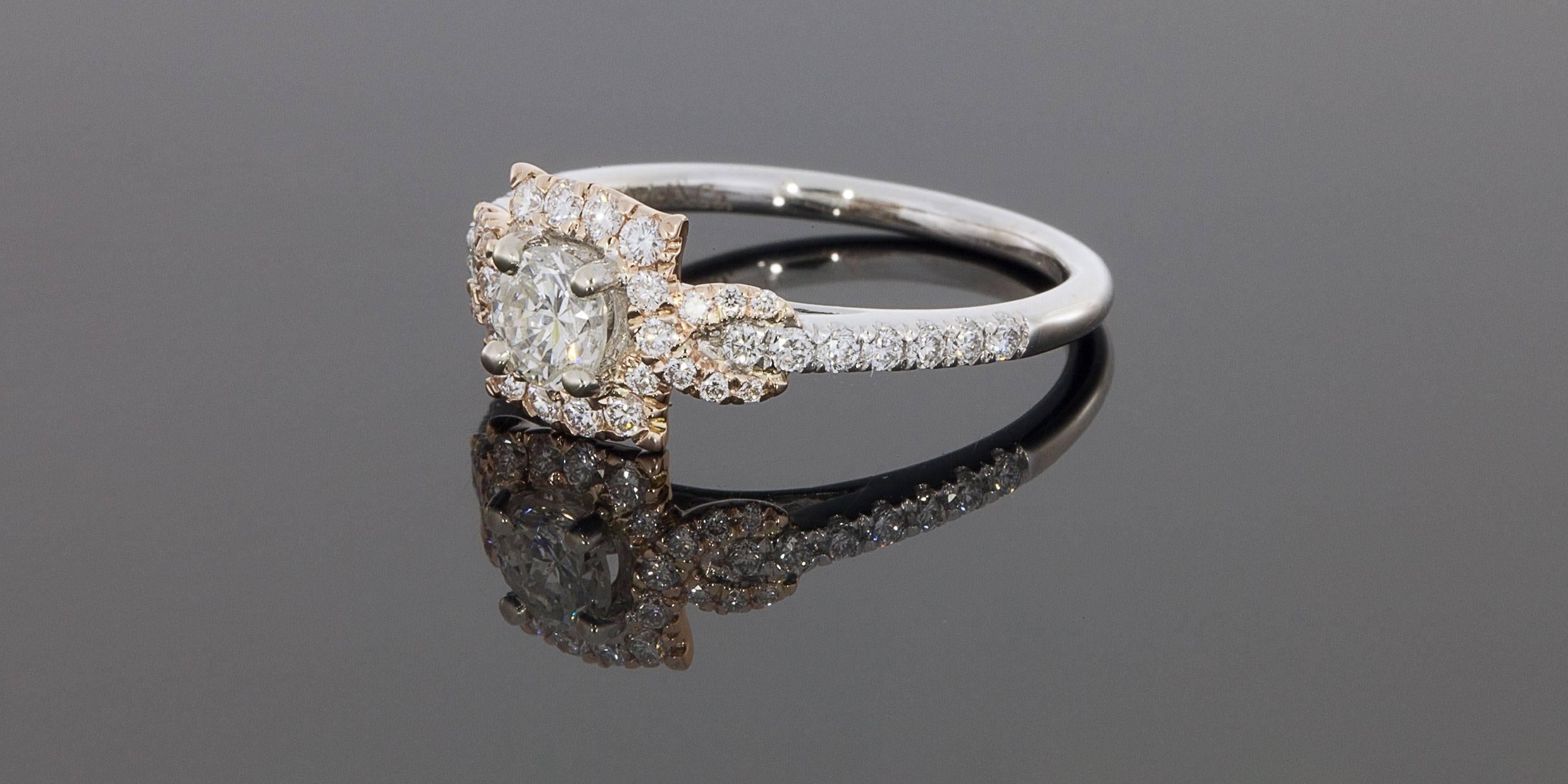 This beautiful rose & white gold engagement ring has a unique halo design that wraps or twists around the shank. The ring features .70 carat total weight in sparkly round brilliant diamonds. The center diamond is a .31 carat round brilliant cut