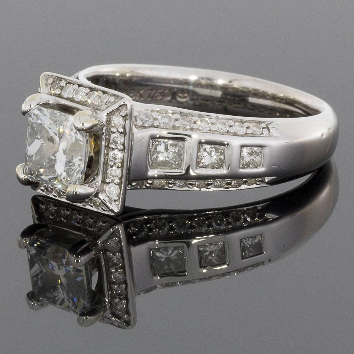 This stunning halo engagement ring has a combined total weight of 1.43 carats and features a center princess cut diamond that weighs approximately .85 carat and grades as G/I1 in quality. This center diamond is split prong set, surrounded by a halo