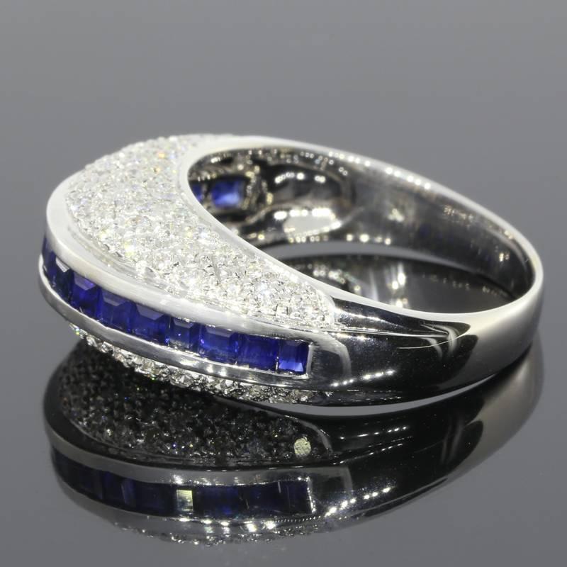 This beautiful & unique band ring features natural, AAA quality, princess cut, blue sapphires & sparkly, GH/SI quality, round brilliant cut diamonds. The sapphires are channel set in the center of the ring. The diamonds are pave set on the top &