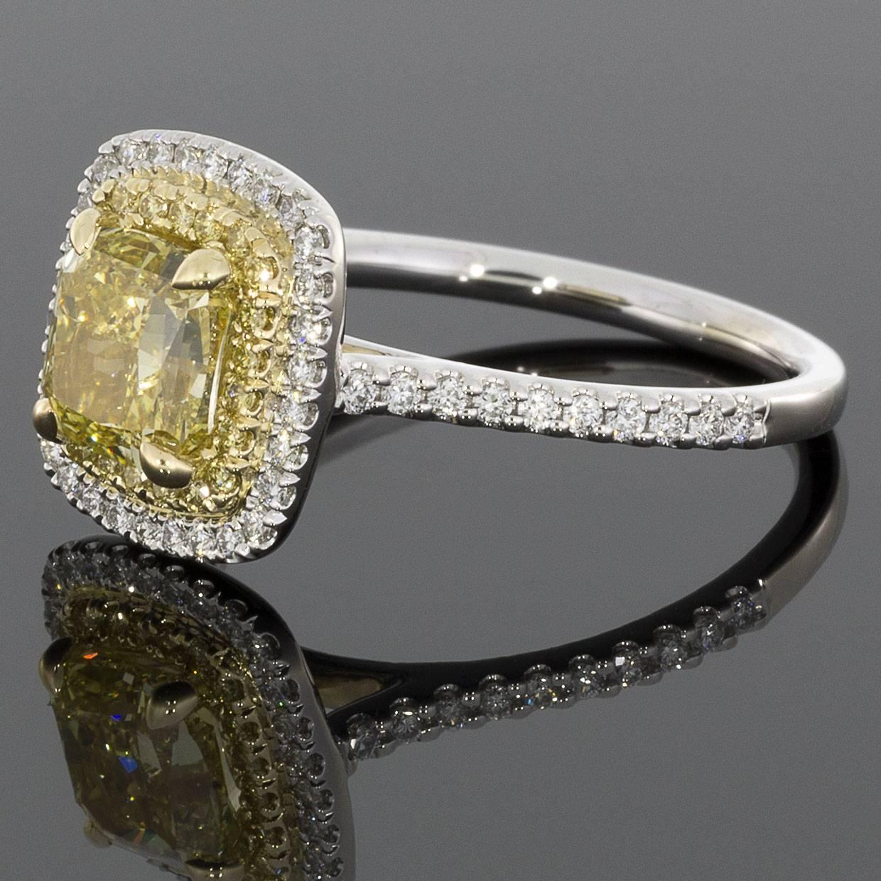 This alluring ring features a classic yet stunning halo design. This design showcases the stunning 1.50 carat, fancy yellow, cushion brilliant cut center diamond that is prong set in a yellow gold head on a custom made ring. This gorgeous center