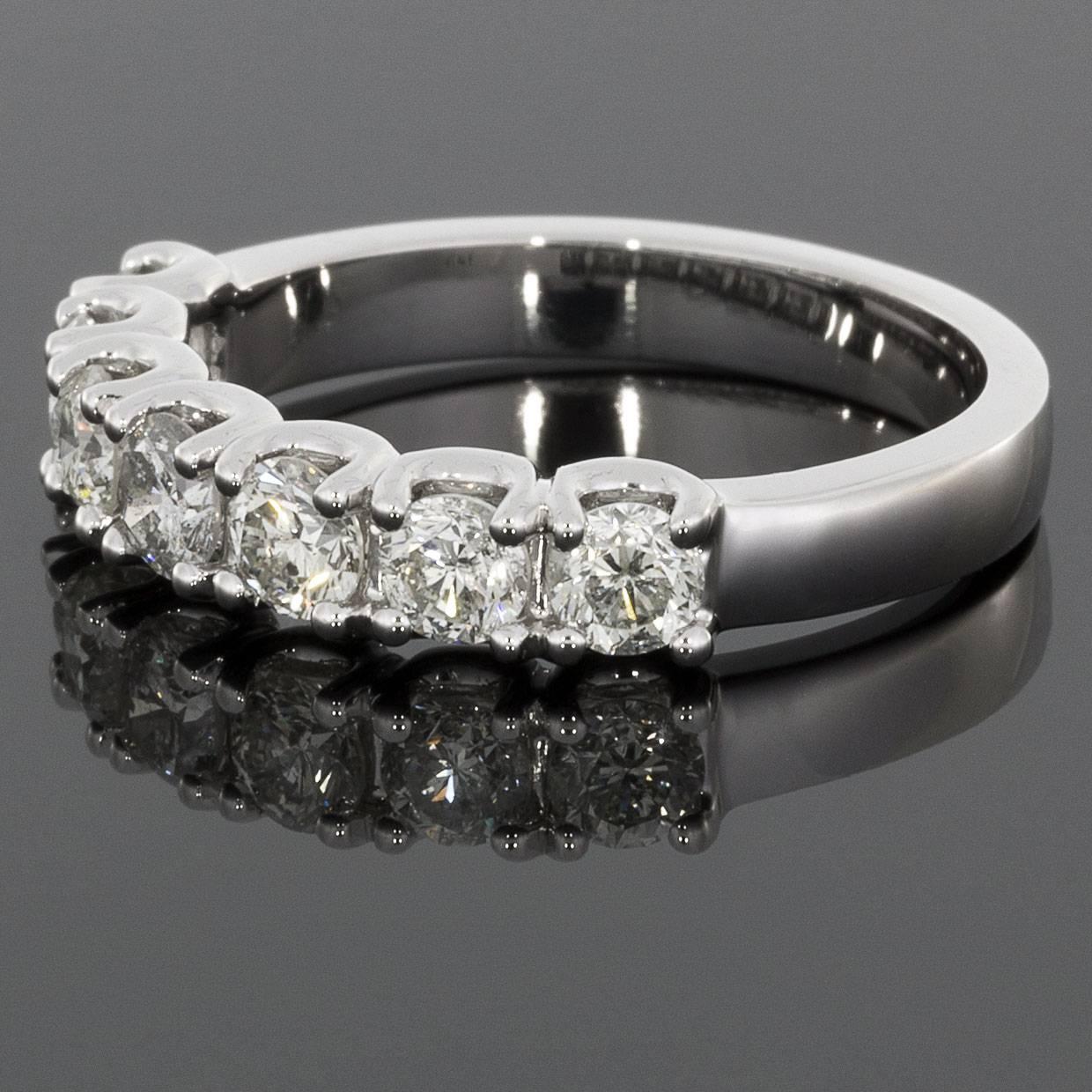 This custom made, classically styled band would make a wonderful wedding band or anniversary ring. The ring is comprised of 14 karat white gold & features 7 round brilliant cut diamonds that have a combined total weight of 1.05 carats. The